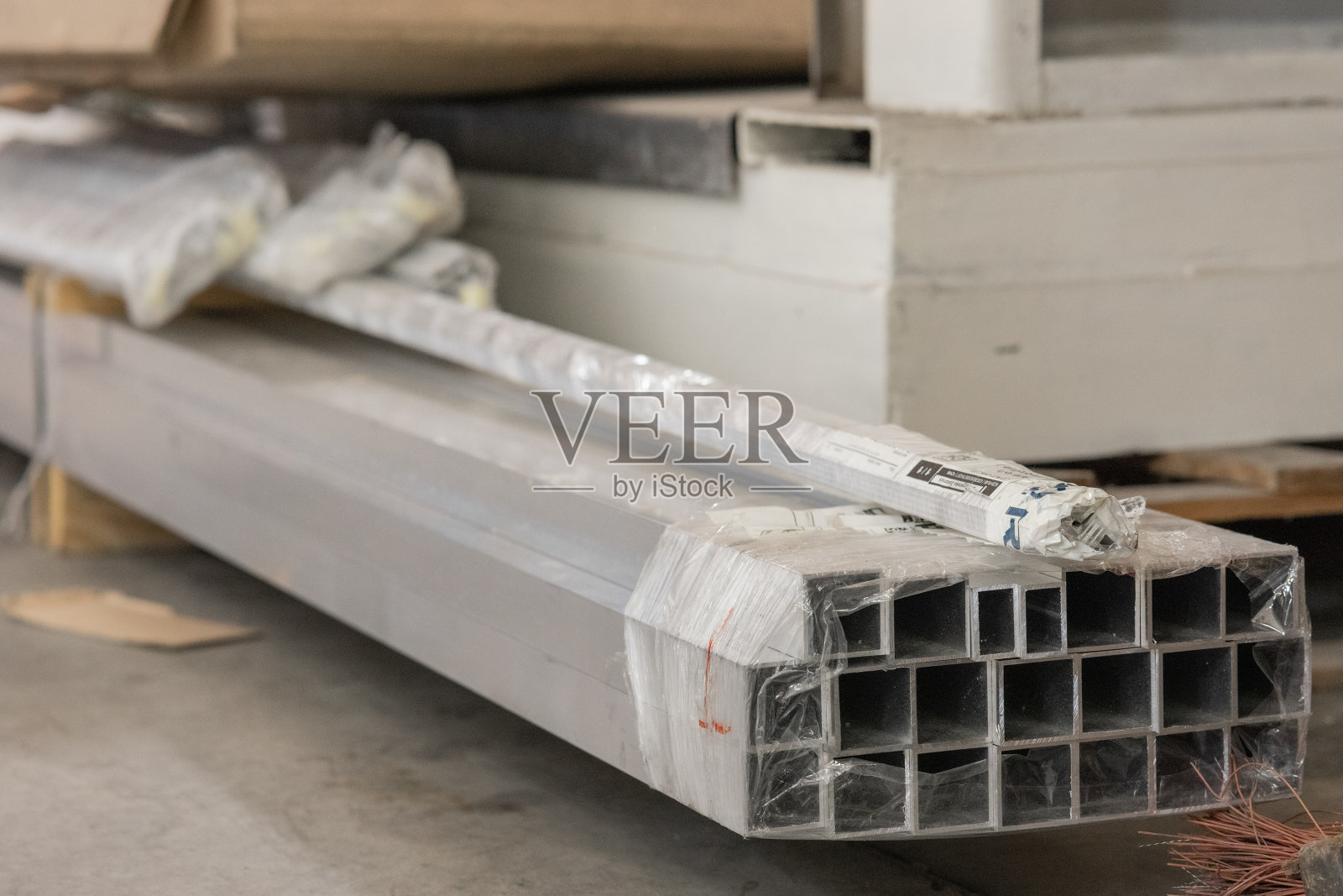 许多或一堆铝型材捆绑在一起，用于激光切割。在地板上批量或包装铝方管。照片摄影图片