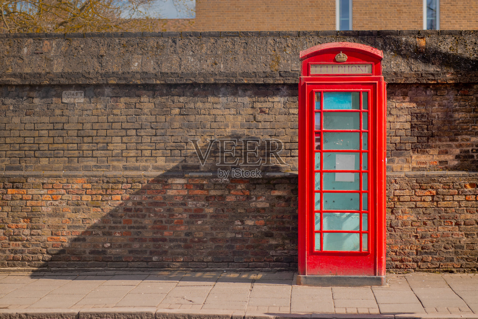 剑桥砖墙上的红色电话亭。老旧照片摄影图片