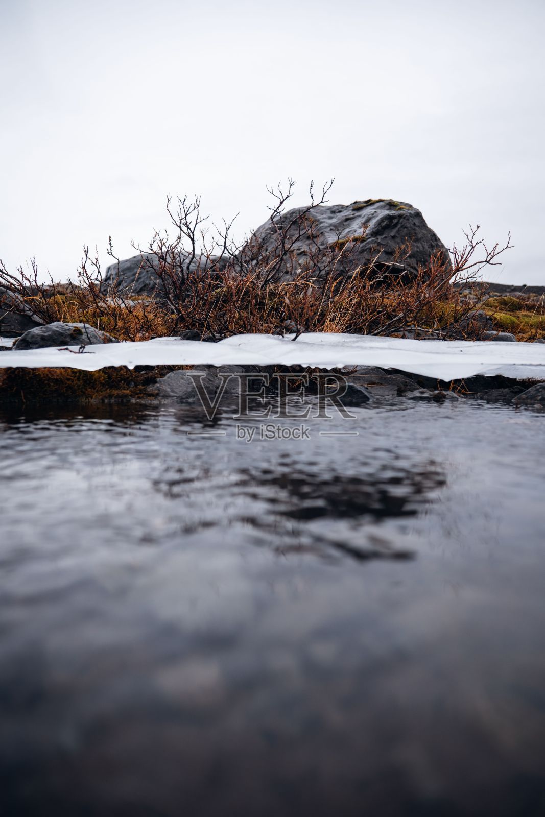 一条蜿蜒的道路旁流淌着一条宁静的小溪，水里可以看到一小块冰照片摄影图片