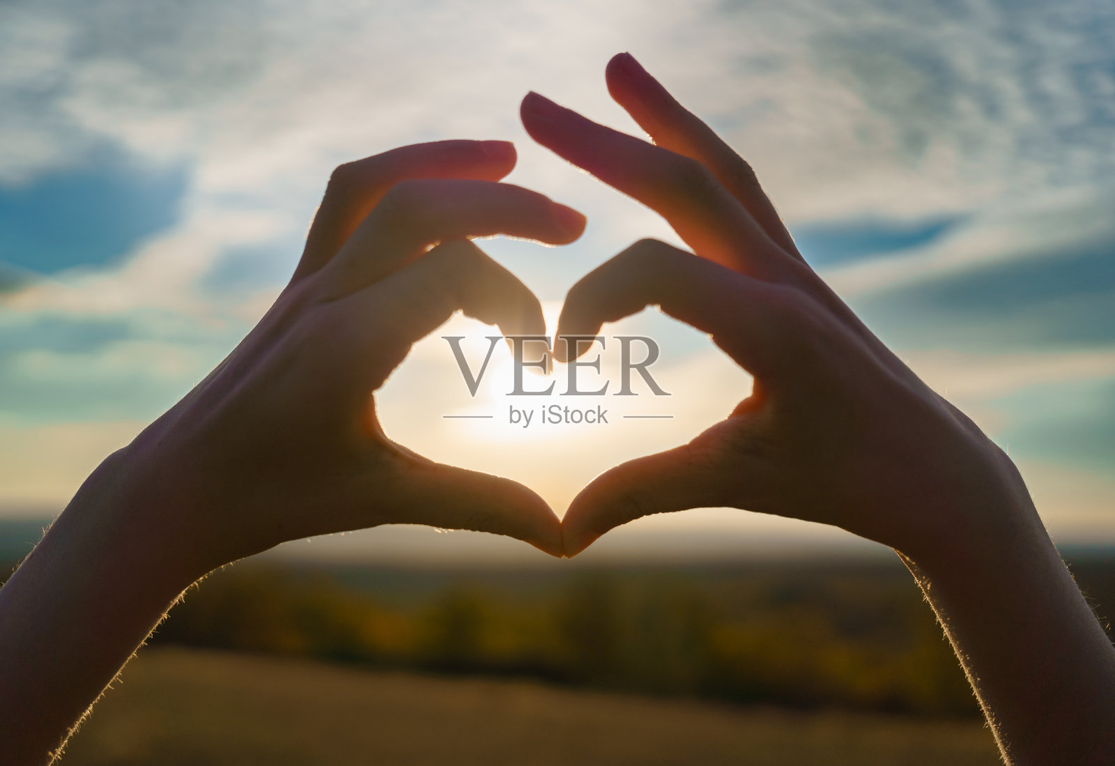 一个女婴的手的轮廓象征着日落时双手的心照片摄影图片