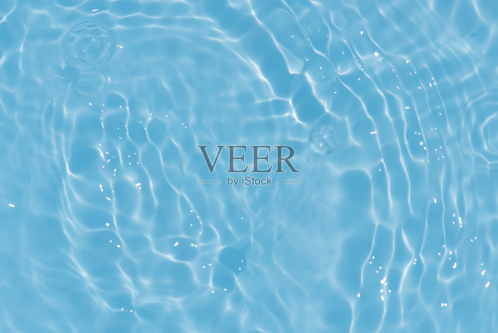 蓝蓝的水面上泛起涟漪。散焦模糊透明蓝色透明平静水面纹理与飞溅和气泡。水波与闪亮的图案纹理背景。照片摄影图片