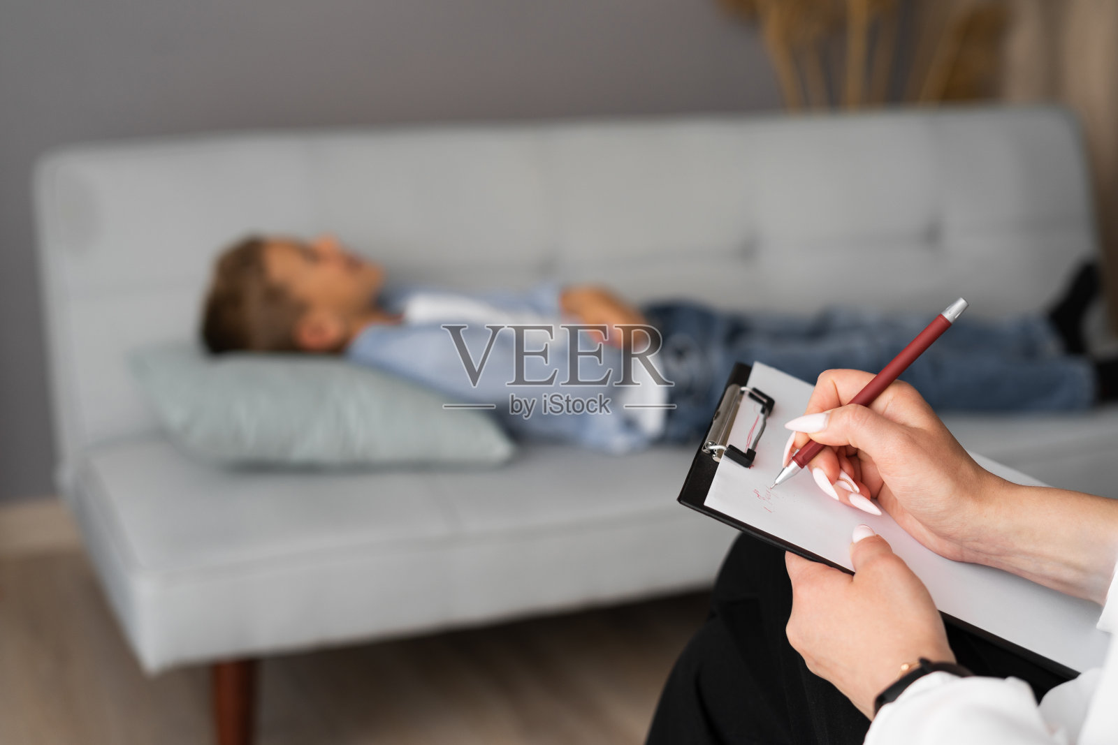 专业精神科医生与她的十几岁的男孩一起工作，并在申请表上做笔记照片摄影图片