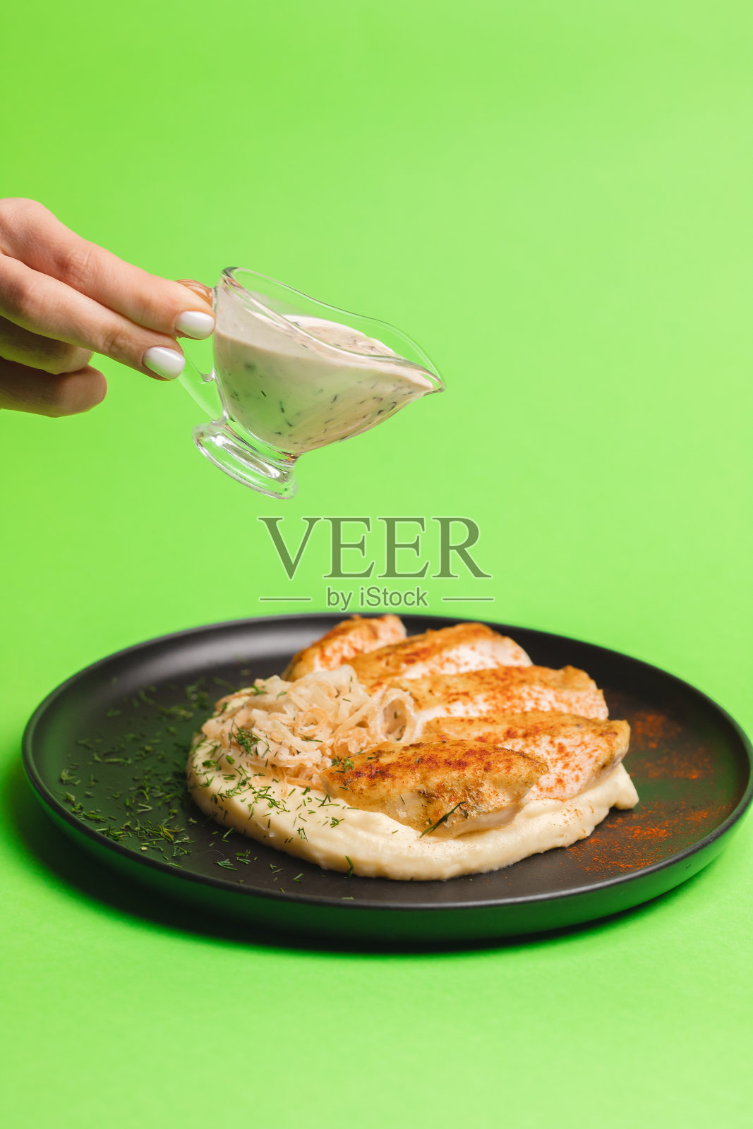 鲜嫩的鸡胸肉配土豆泥，在浅绿色的底色上浇上酱汁。照片摄影图片