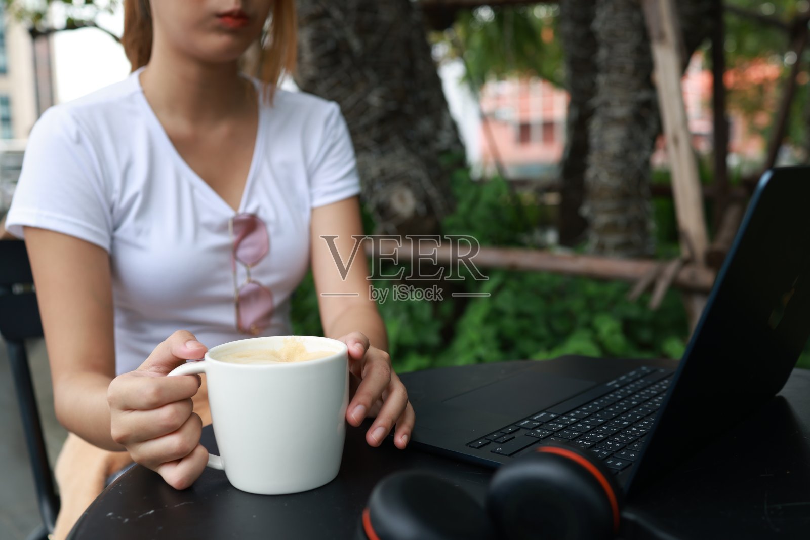 年轻的千禧一代亚洲女性在城市里用笔记本电脑工作，享受着热饮。到处都是一个工作概念照片摄影图片