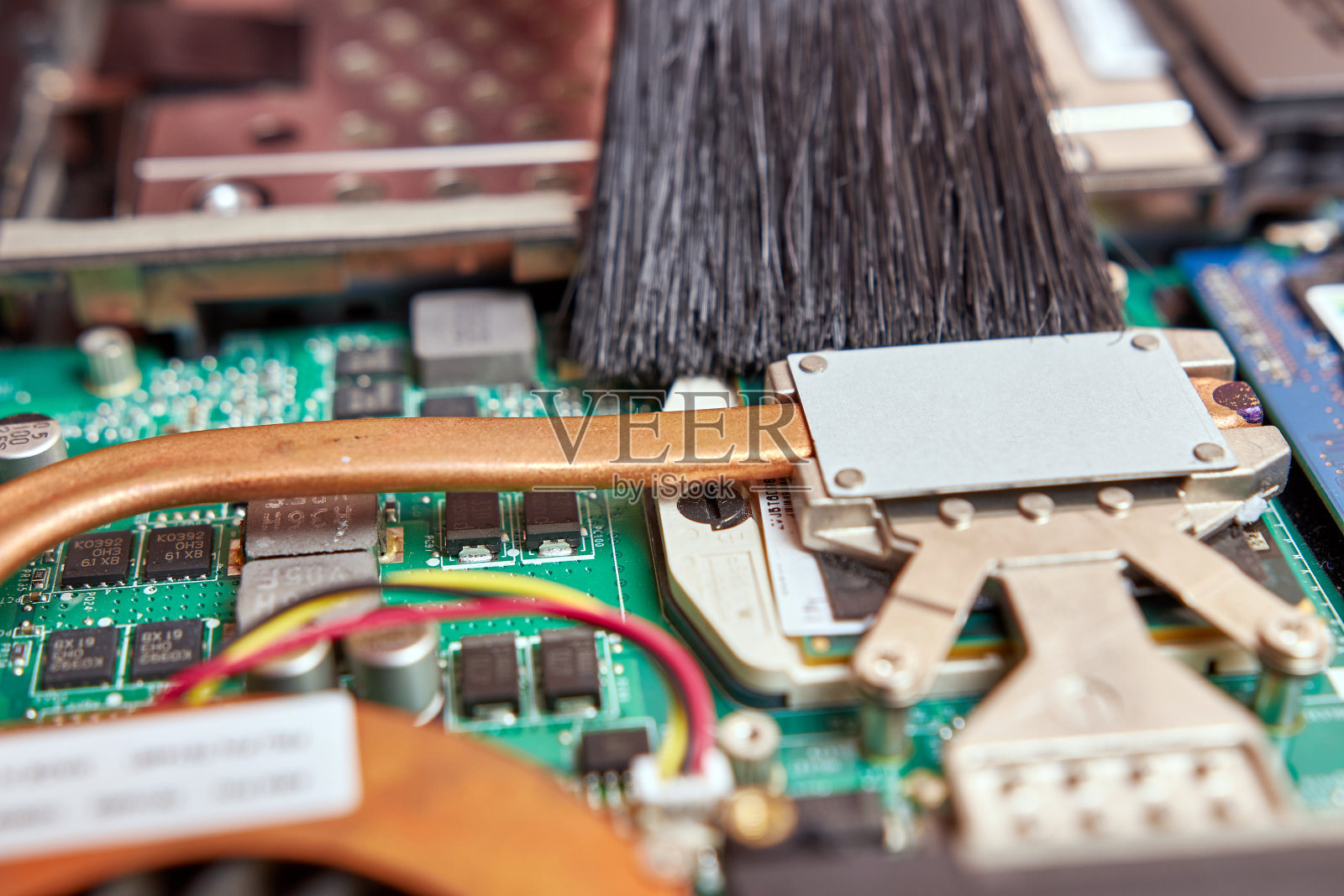 向导用刷子和吸尘器清洁笔记本电脑的冷却系统。个人电脑保养和维修理念。照片摄影图片