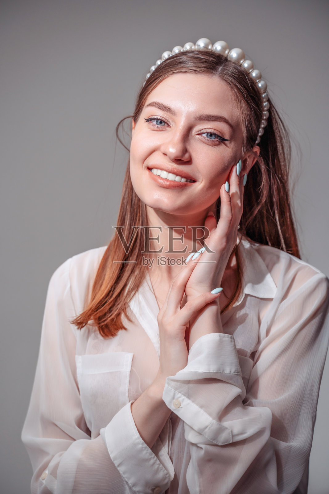 时髦的年轻女子穿着白色休闲服装，看着别处微笑着。照片摄影图片
