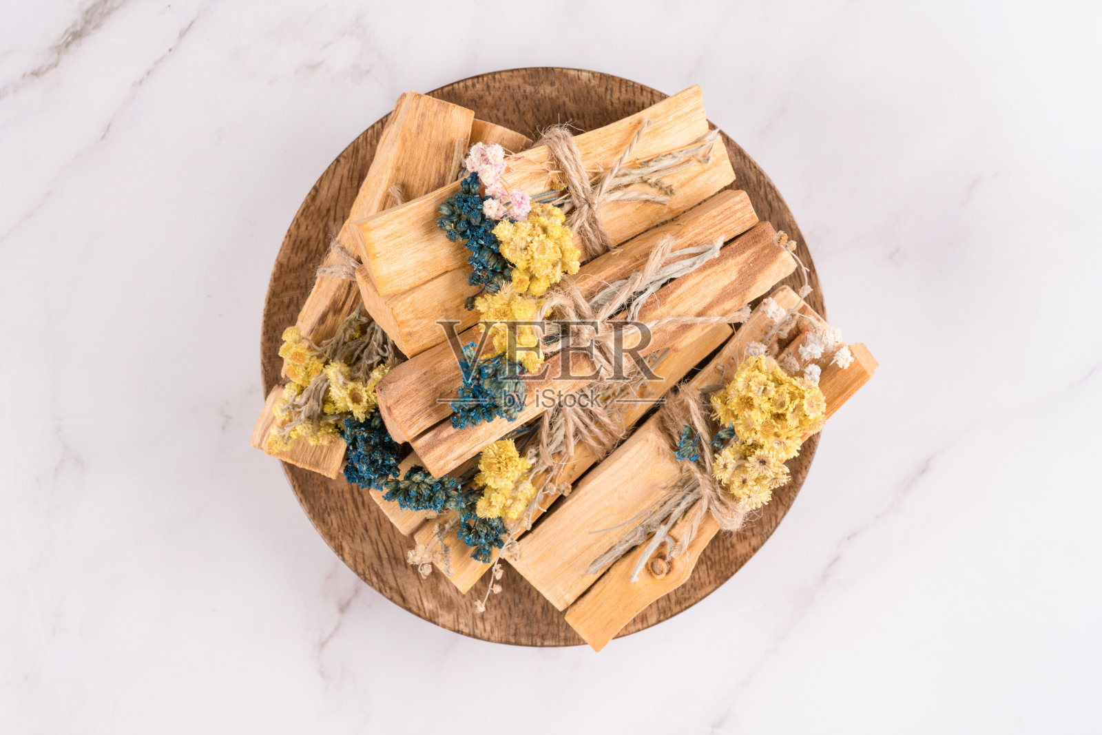 在白色大理石桌子背景上的冥想和精神实践的神圣木棒的顶部视图。帕罗桑托把干花花束放在木托盘上。阿育吠陀宗教仪式照片摄影图片