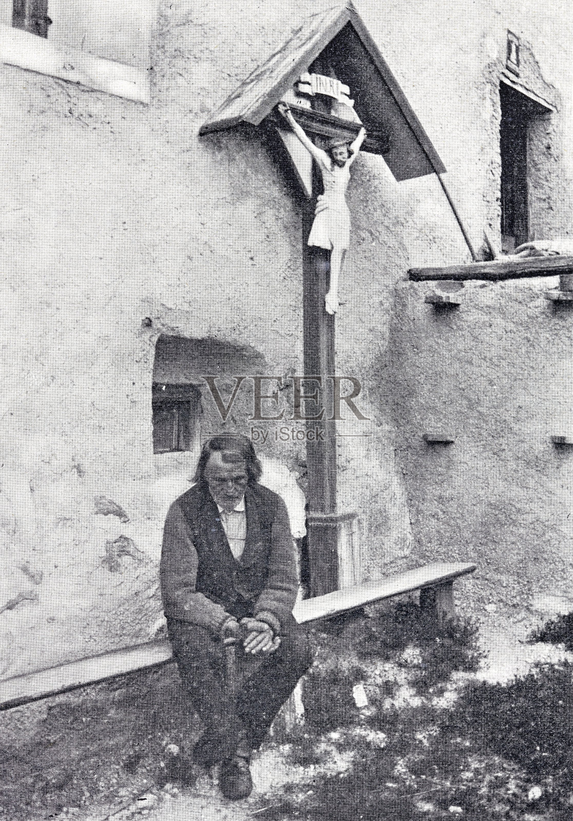 在教堂前的墓地，一个人坐在木制长凳上，在十字架旁边祈祷万福玛利亚插画图片素材