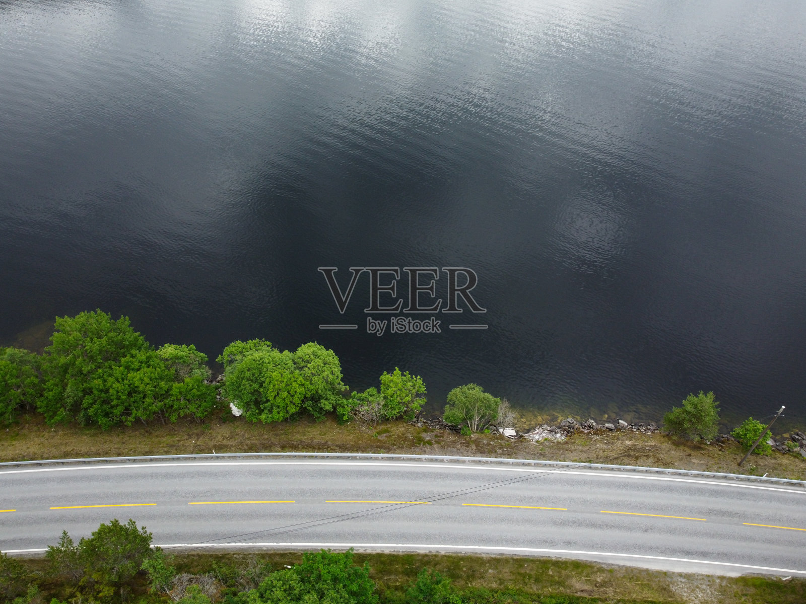 鸟瞰图，无人机拍摄的一条狭窄的山峡谷公路，旁边是一个蓝色的湖水。照片摄影图片