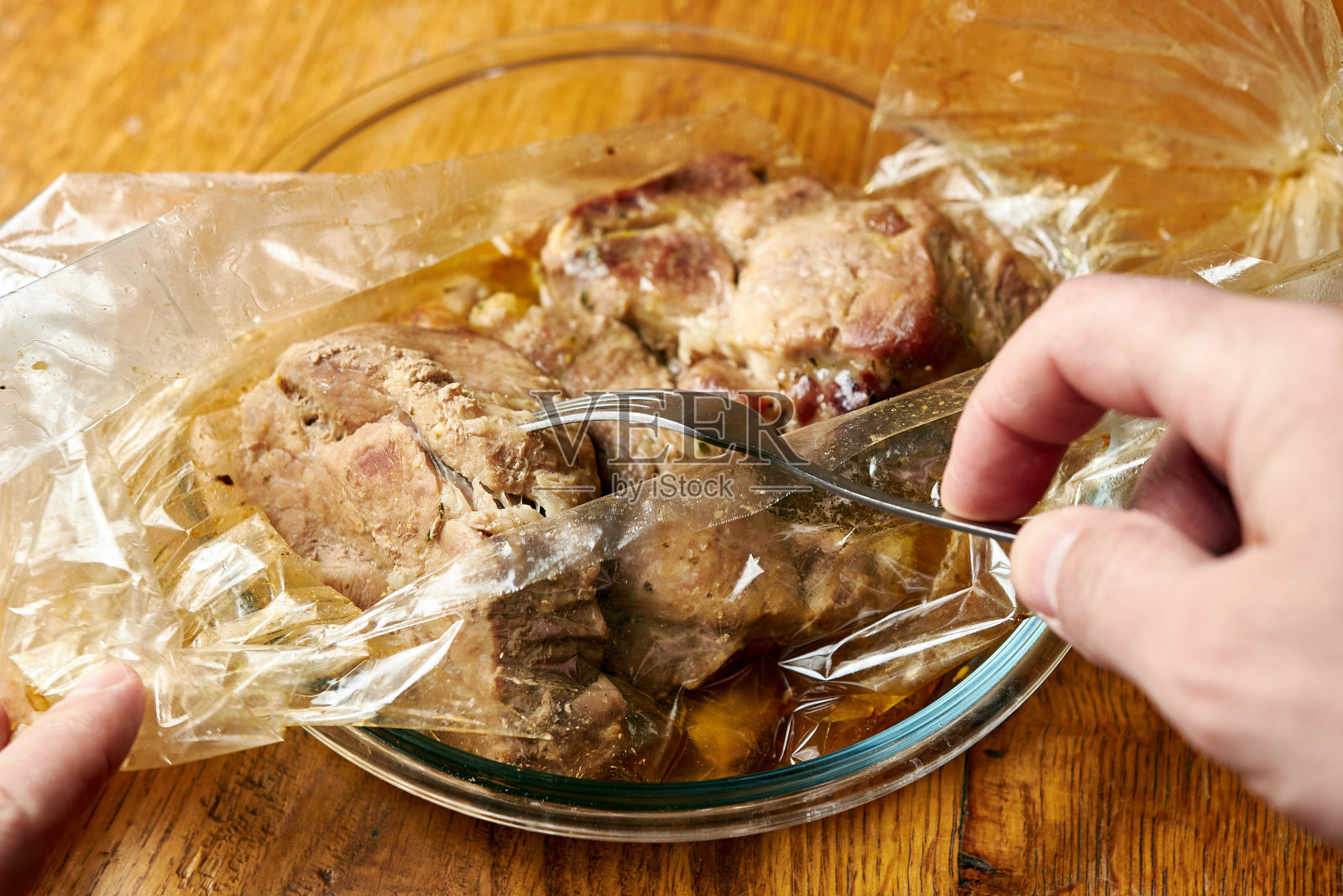 准备一道菜，从一堆烤在一个袋子里烘烤。厨师用叉子检查菜是否做好了。照片摄影图片