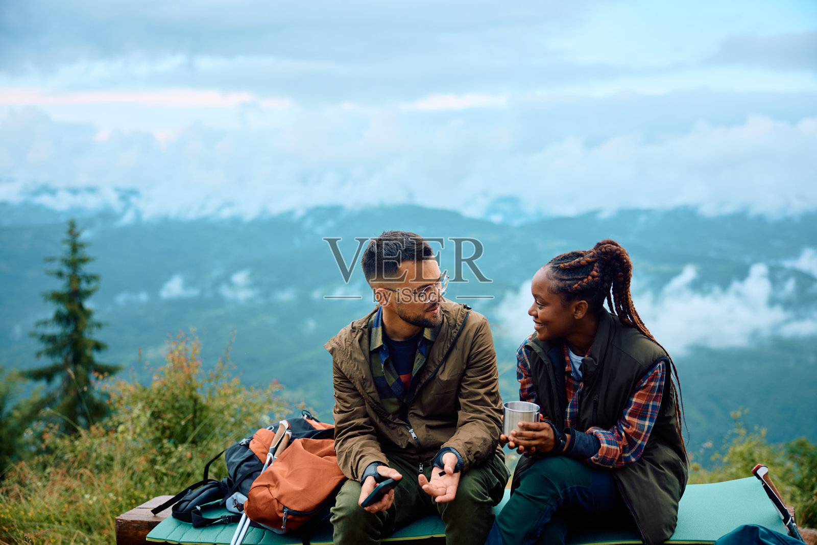 年轻的爱冒险的夫妇聊天，放松的父亲在山上徒步旅行。照片摄影图片