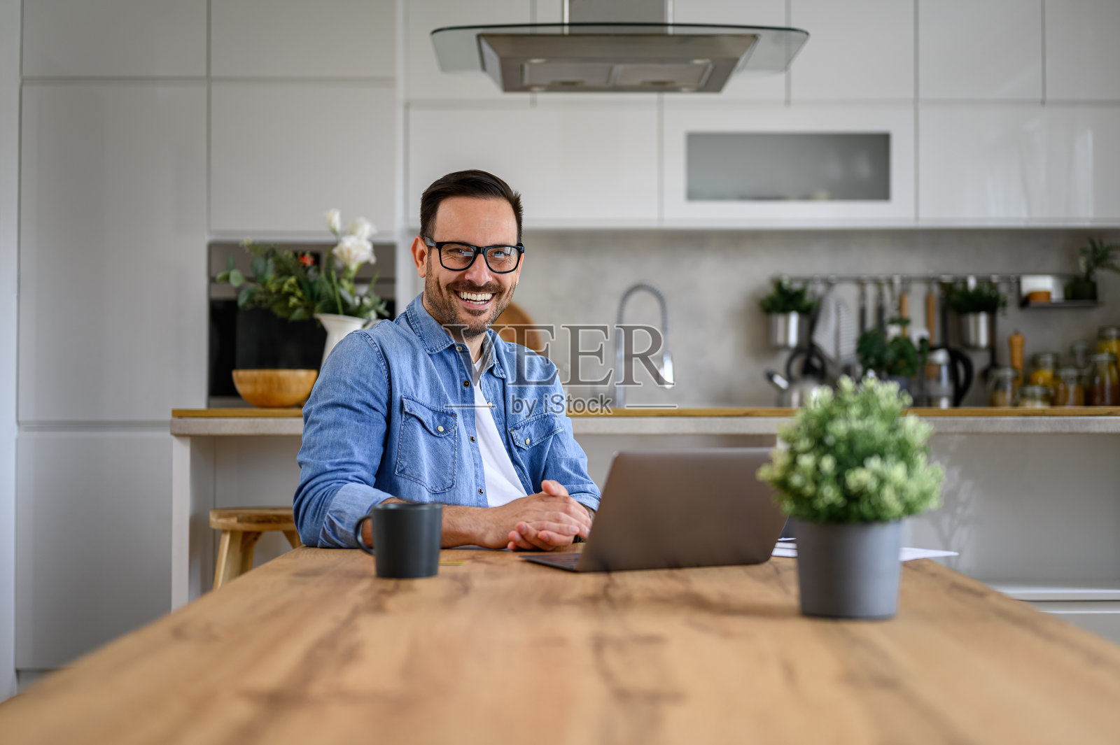 成功企业家的肖像，桌上放着笔记本电脑，坐在家里的办公室里，对着镜头微笑照片摄影图片