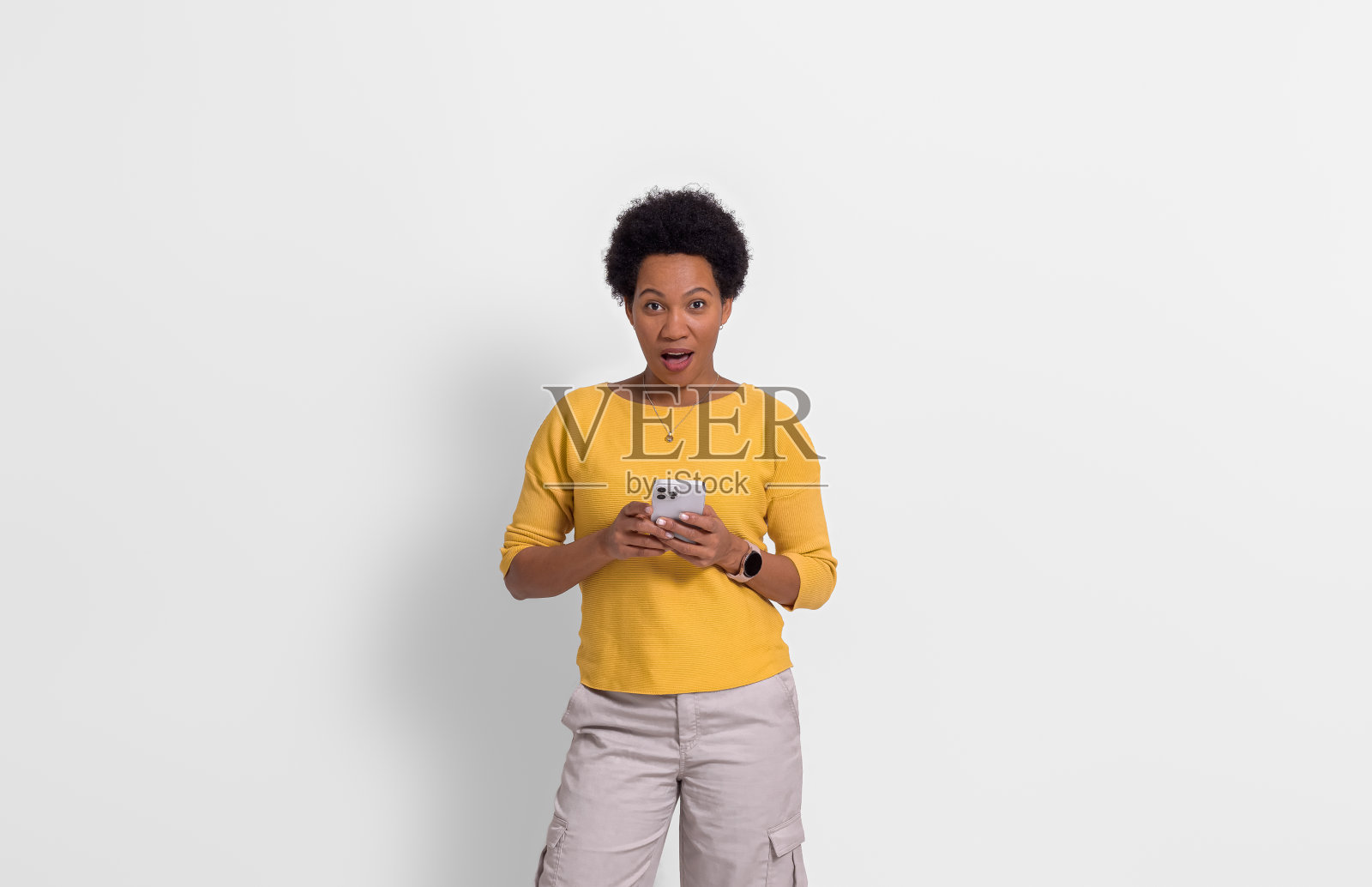 一个留着非洲式发型的年轻女子正在用白色背景的智能手机读短信照片摄影图片