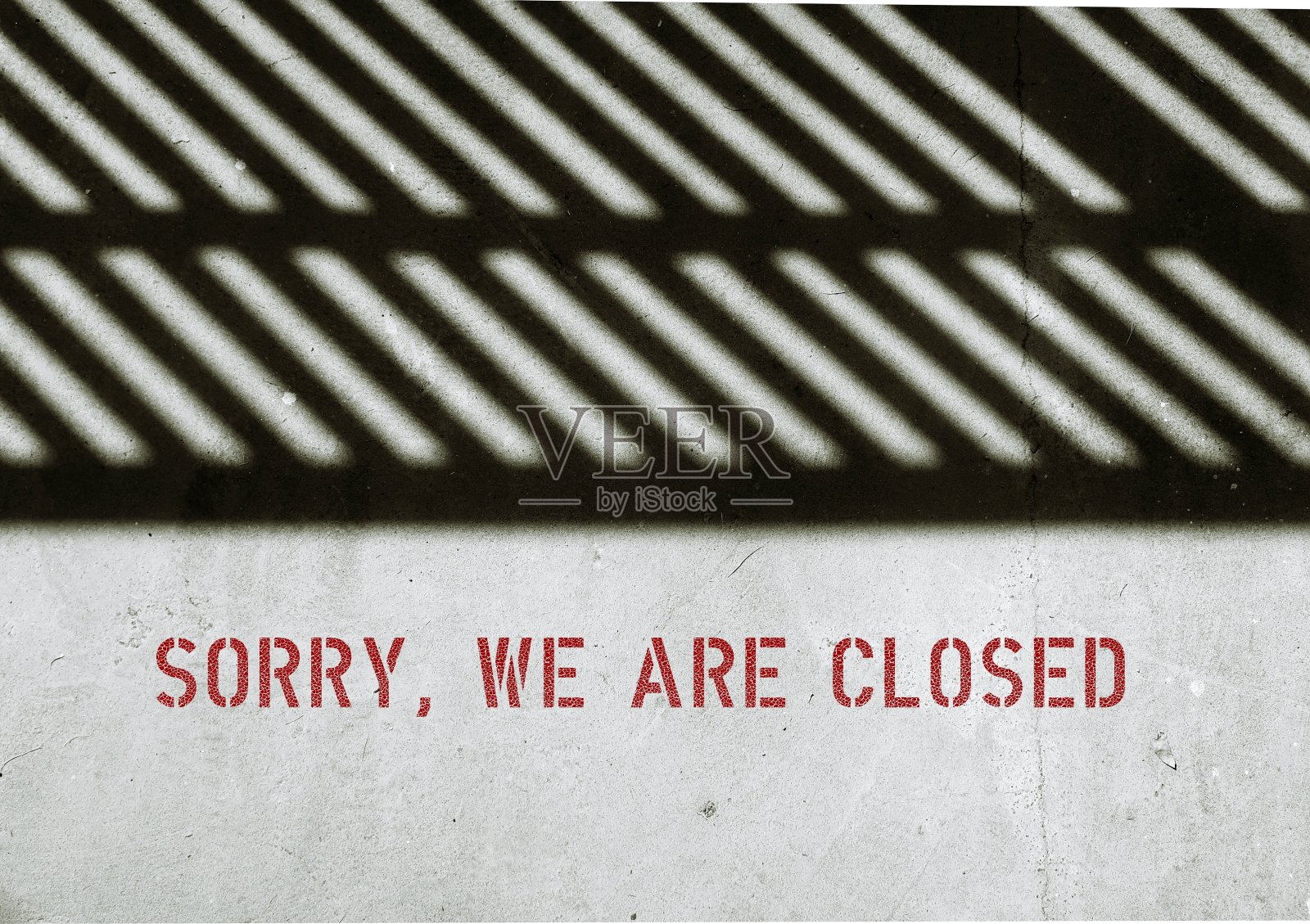 水泥背景上的栅栏阴影，带有屏幕文字对不起，我们关门了，通知顾客商店关门时间，或由于经济不景气而关门或停业照片摄影图片
