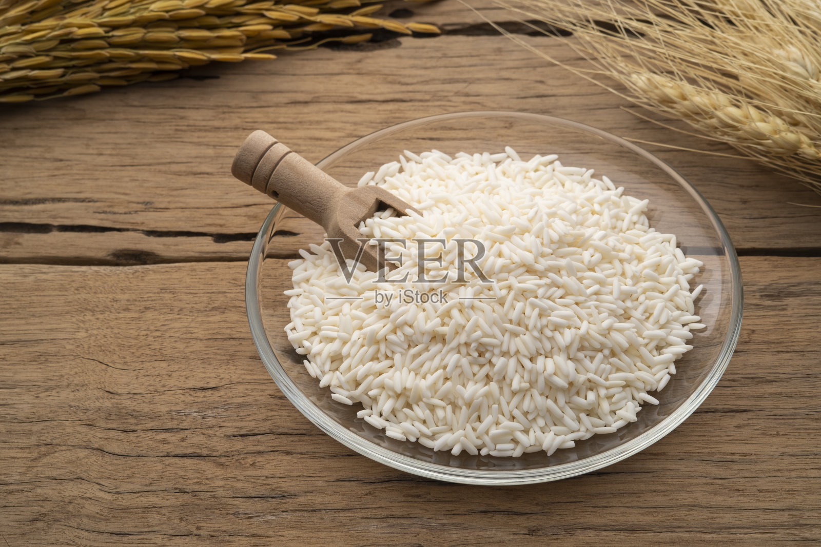 木桌上的玻璃盘里装着未煮熟的泰国糯米照片摄影图片