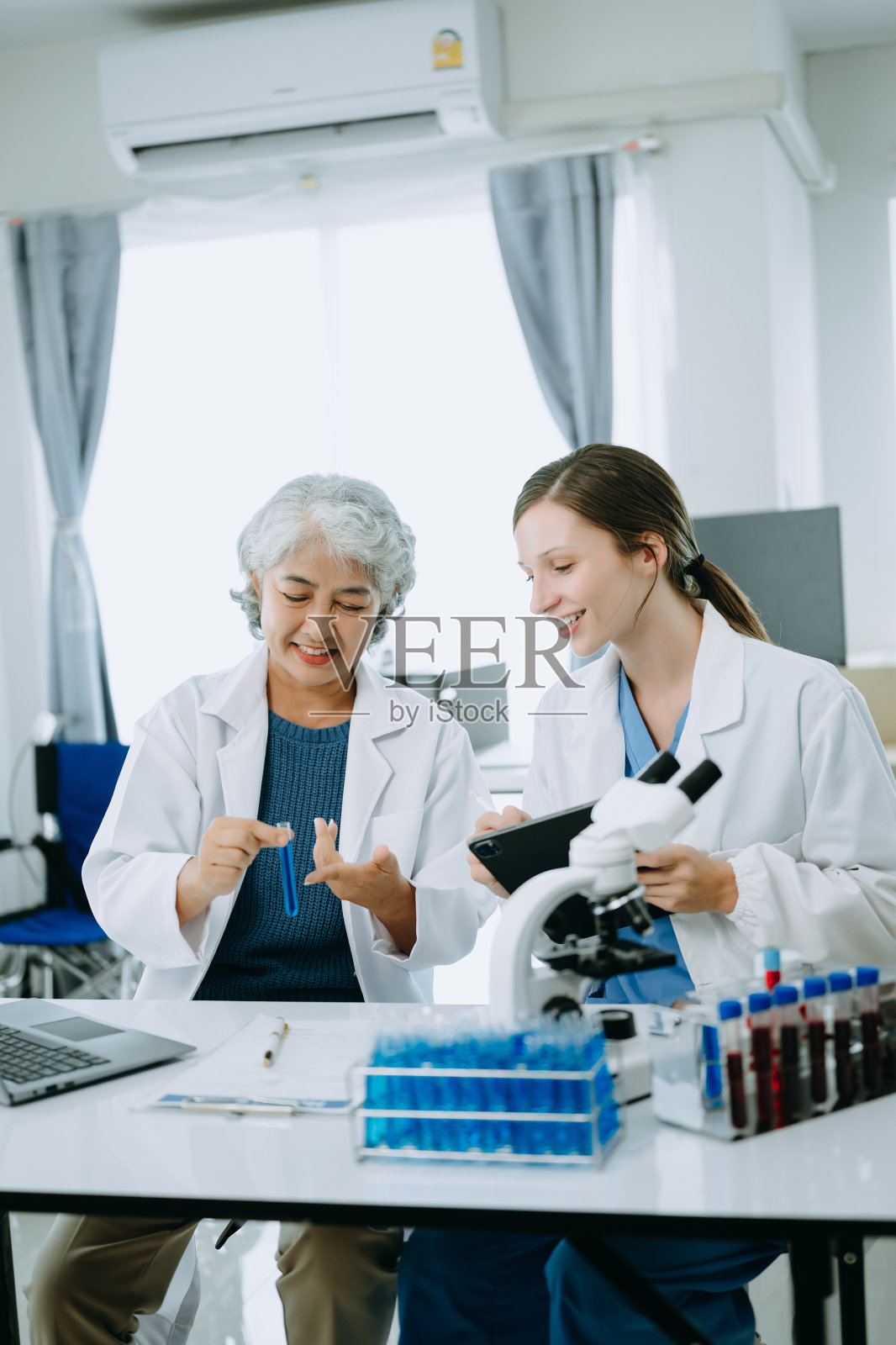 两名科学家或医疗技术人员工作，与一名亚洲高级女科学家主管在实验室进行医学讨论会议，在线阅读，测试样本和创新全球变暖，分析照片摄影图片