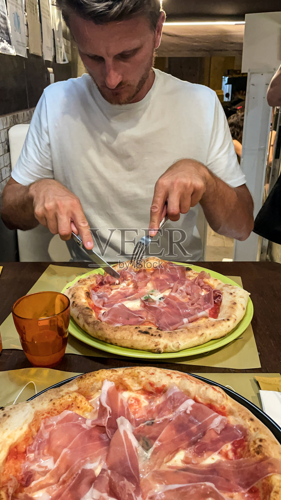 一个男人在餐馆的餐桌上吃披萨照片摄影图片