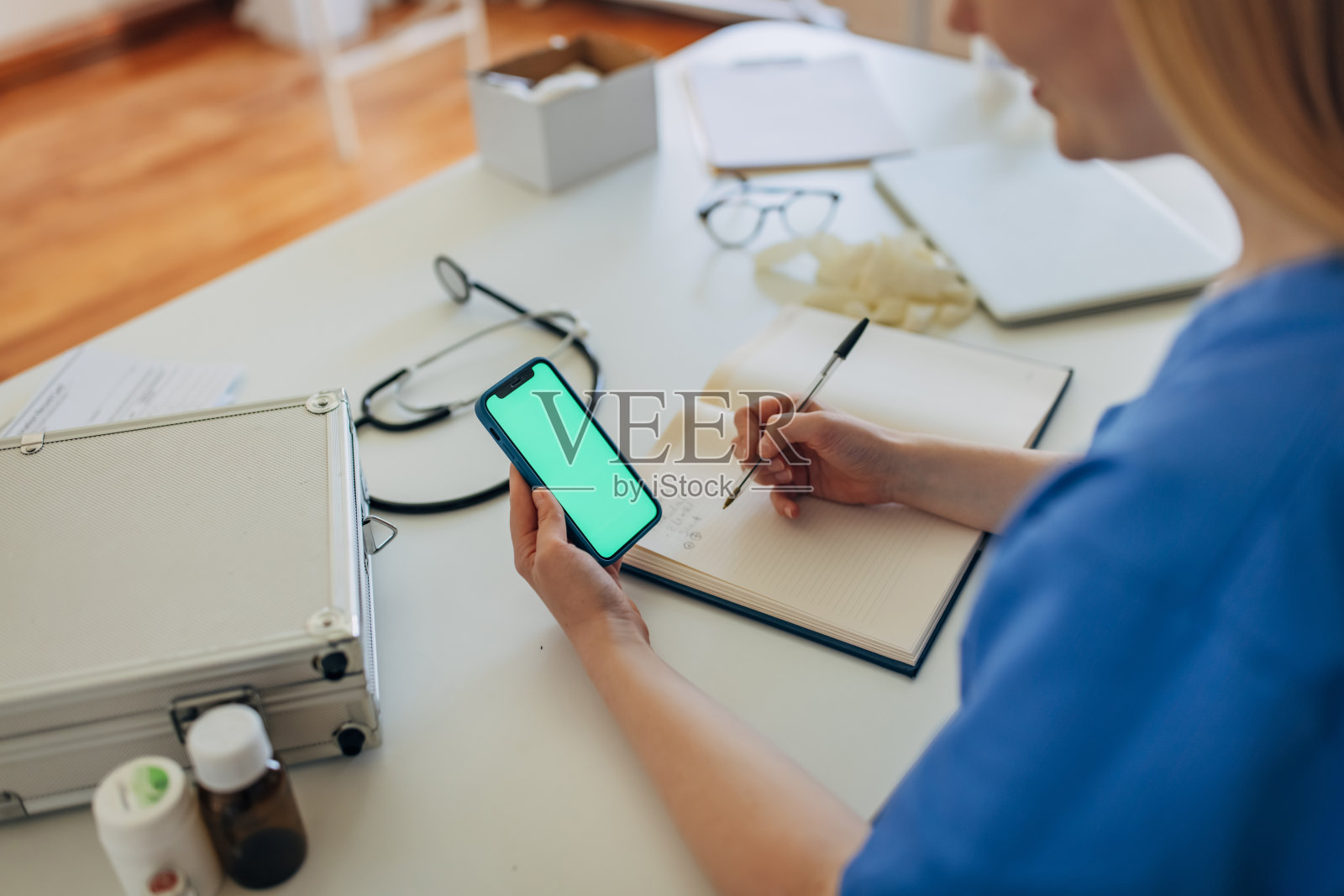 女护士坐在诊所的服务台，使用智能手机照片摄影图片