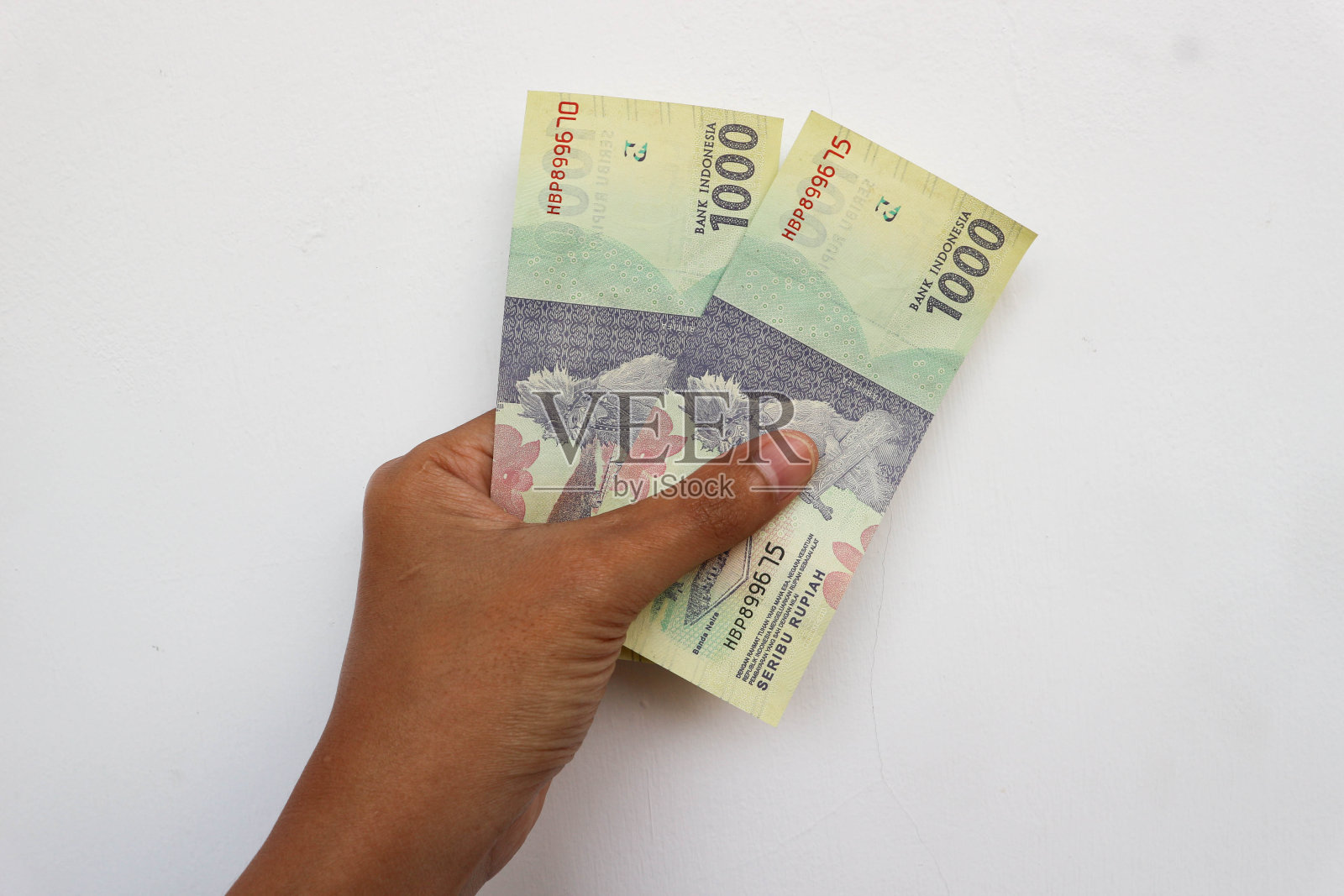 手里拿着两张一千卢比的钞票。印尼盾照片摄影图片