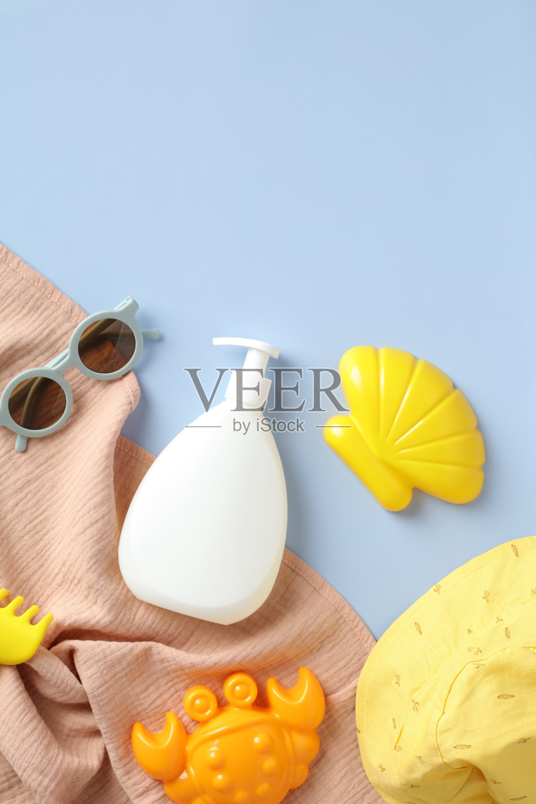 平铺防晒乳液瓶模型的孩子，太阳镜，沙模，巴拿马帽，毛巾在蓝色的背景。阳光安全儿童和婴儿的概念。照片摄影图片