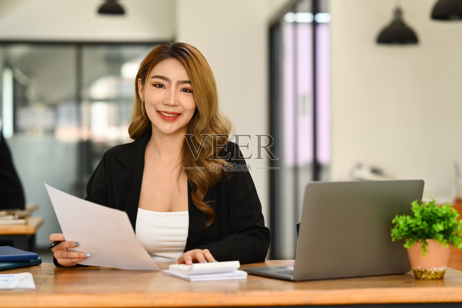 亚洲女性投资者使用笔记本电脑，在办公室处理财务文件的肖像。照片摄影图片