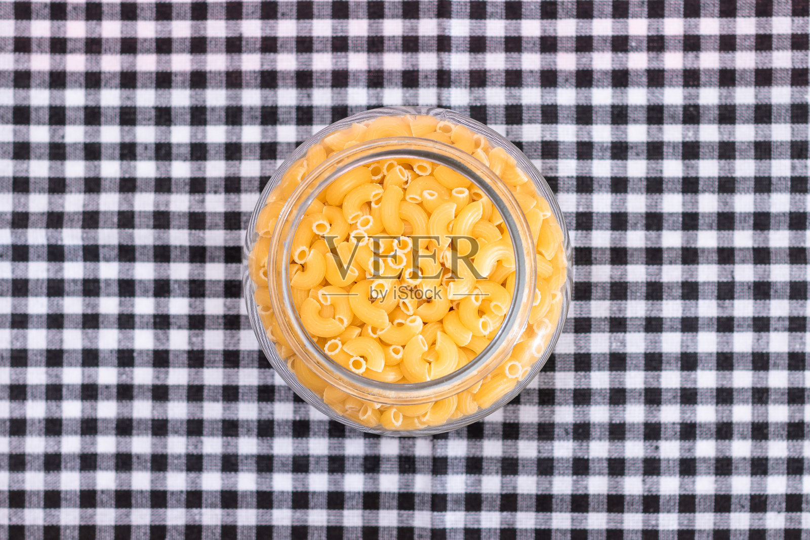 未煮熟的意大利面在黑色方格毛巾的玻璃罐中照片摄影图片