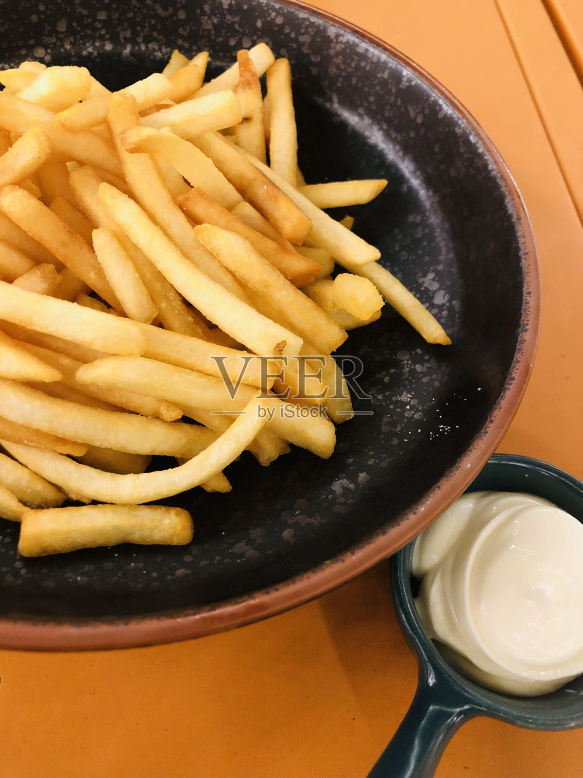 盘子里的炸薯条和桌子上的蛋黄酱的特写镜头照片摄影图片