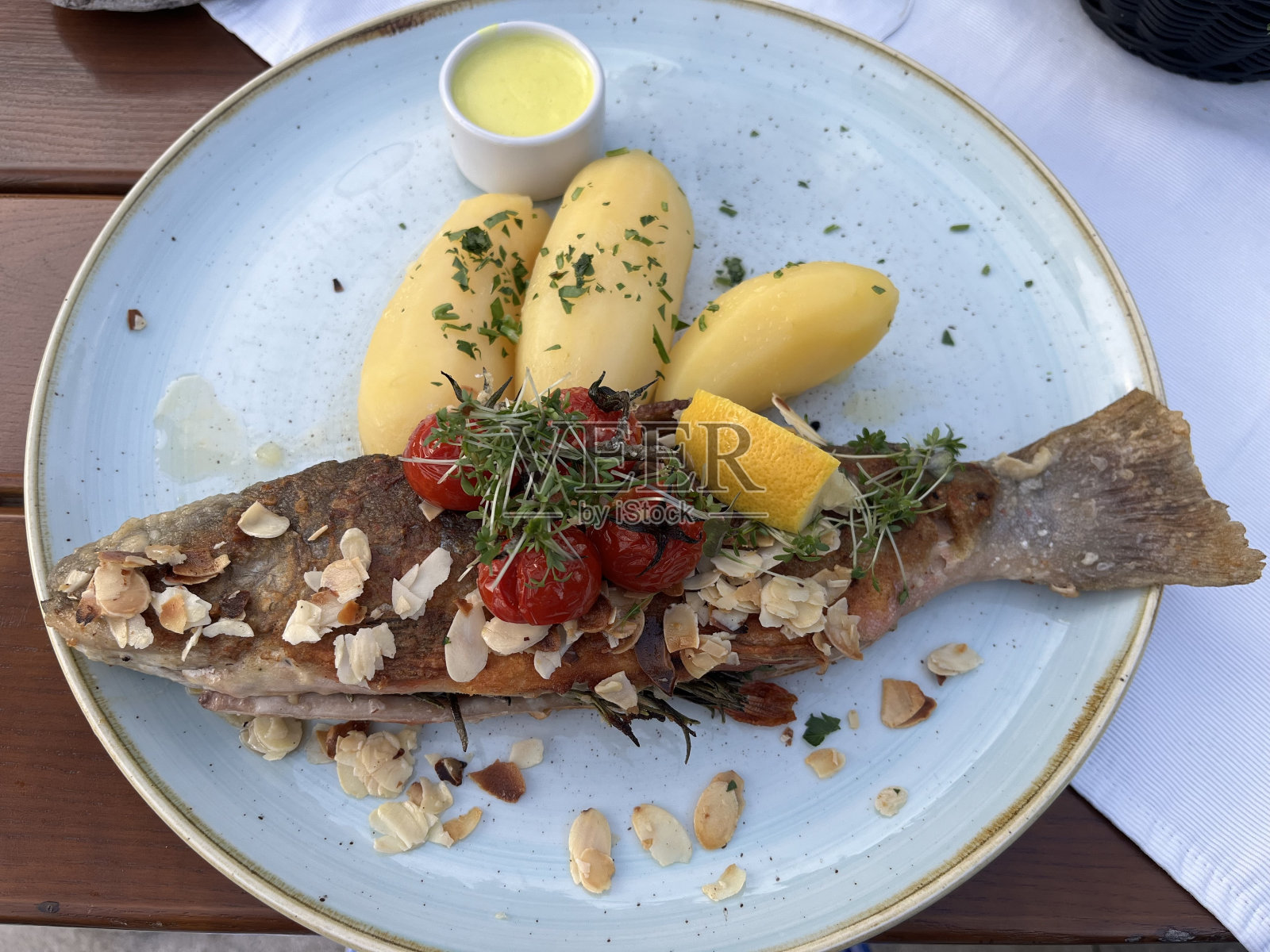 整条炸鱼放在盘子里。一盘炸鱼和煮土豆。土豆煎炭。照片摄影图片