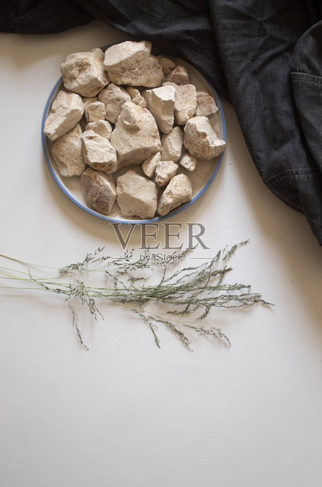 白色的粘土石头和干叶子在白色的背景上照片摄影图片