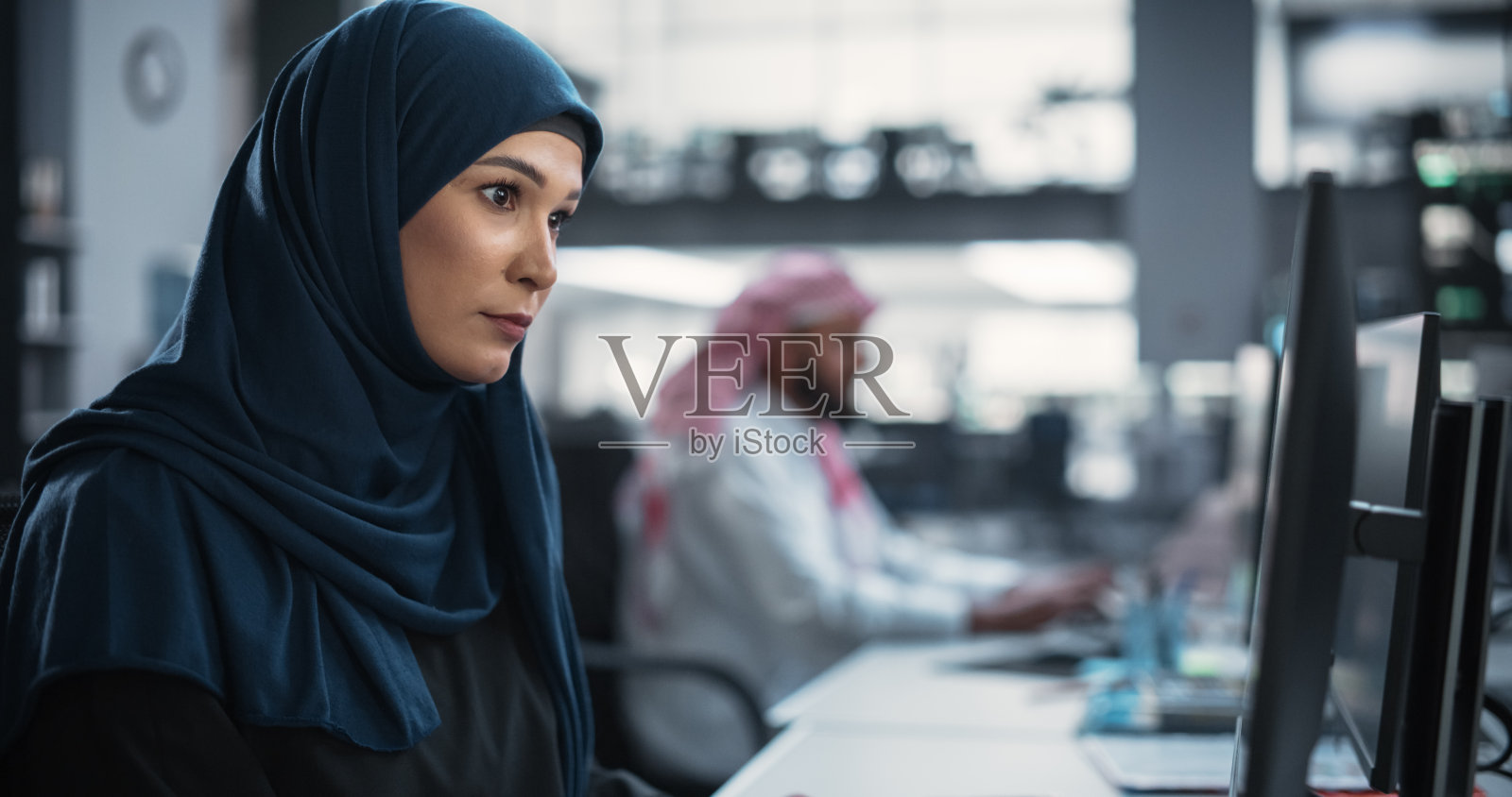 一位有思想的中东工程师在一家科技公司的办公室里工作。为创新互联网和软件即服务项目编写软件代码的年轻女性照片摄影图片