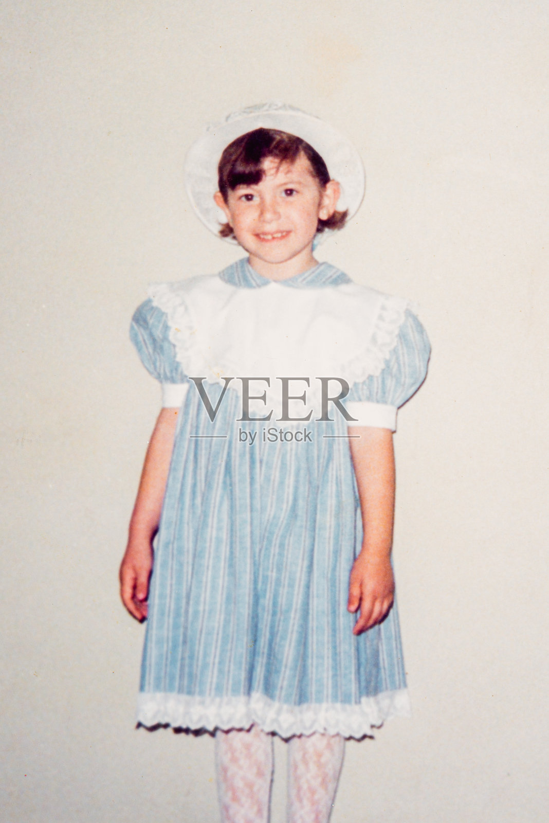 90年代巴西，穿着蓝色裙子和帽子的女孩看着相机的复古肖像照片摄影图片
