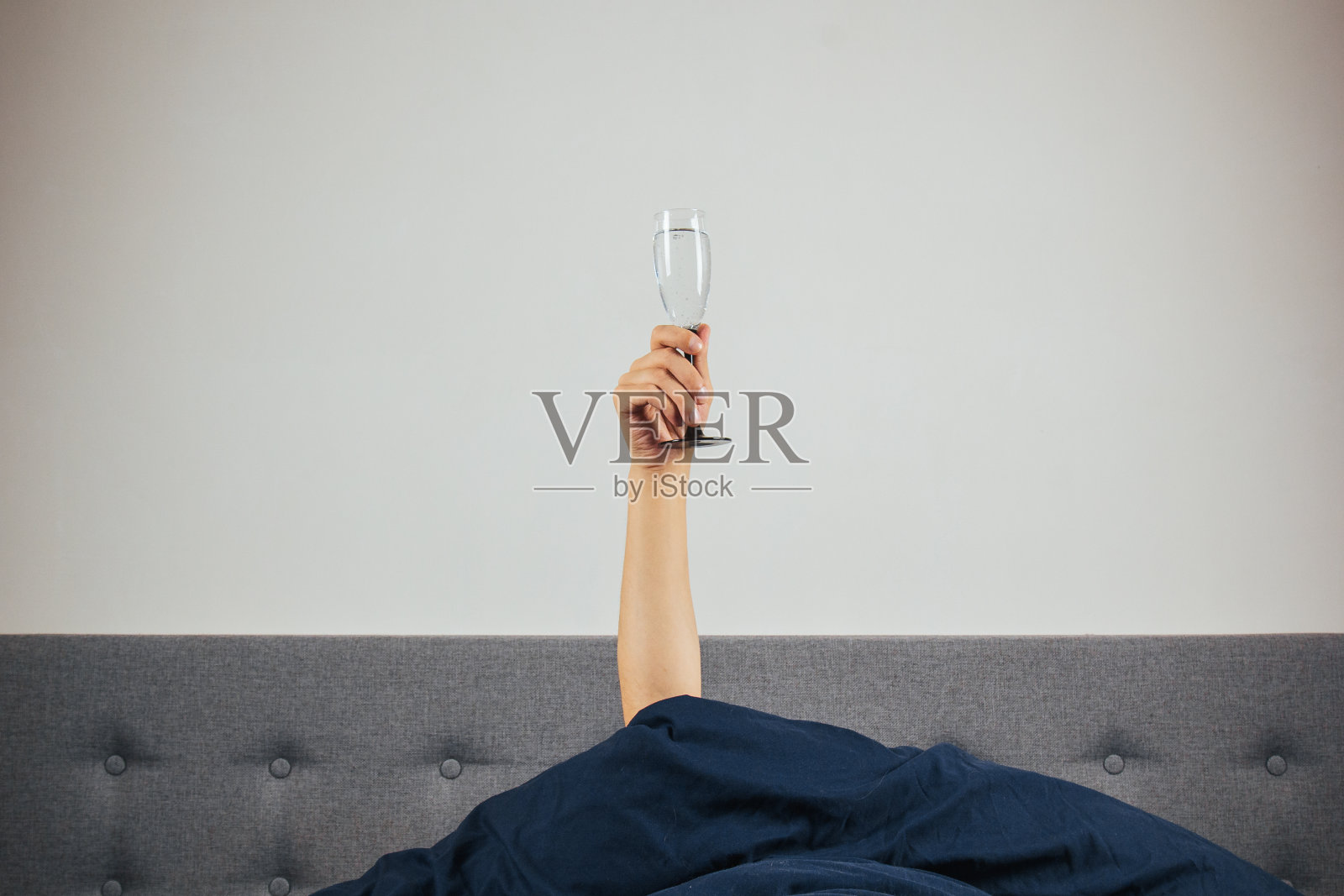 床上男人手里拿着香槟。宿醉、酒精中毒的概念。节日的问候。照片摄影图片