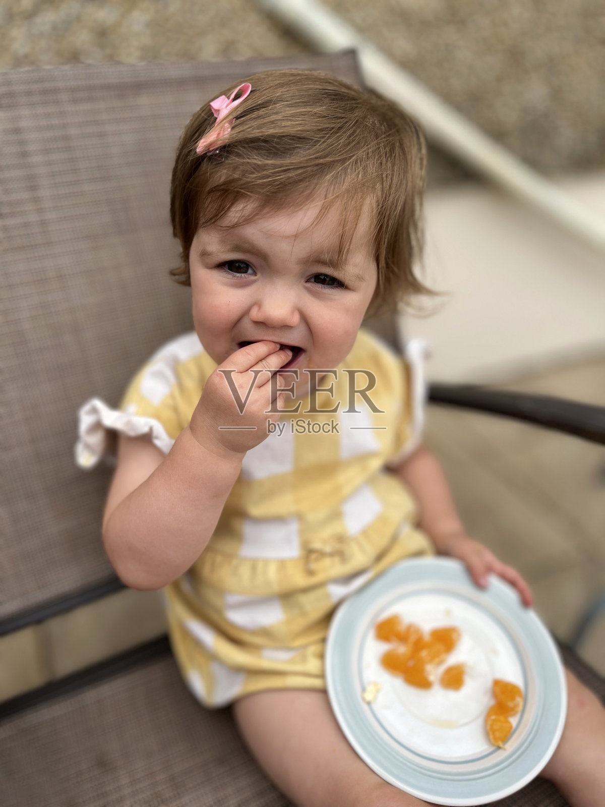 18个月大的女孩吃橘子的肖像照片摄影图片