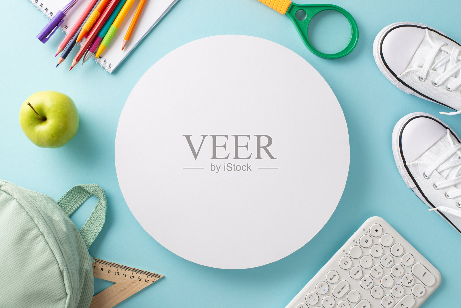 用现代技术理念学习。上面的帆布背包，一双运动鞋，键盘和文具与空圈复制空间孤立的淡蓝色背景的照片照片摄影图片