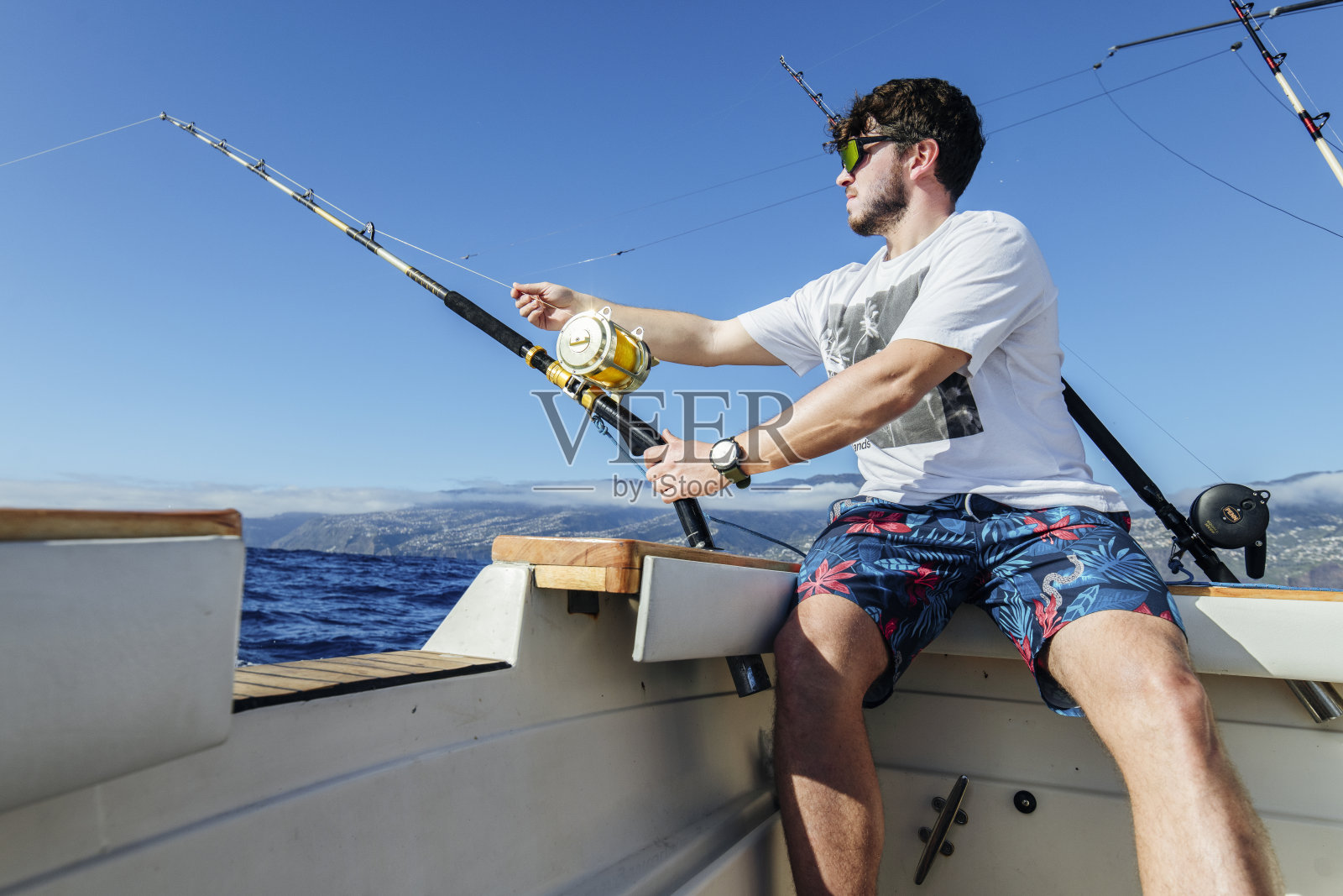 一个人坐在船上钓金枪鱼。照片摄影图片
