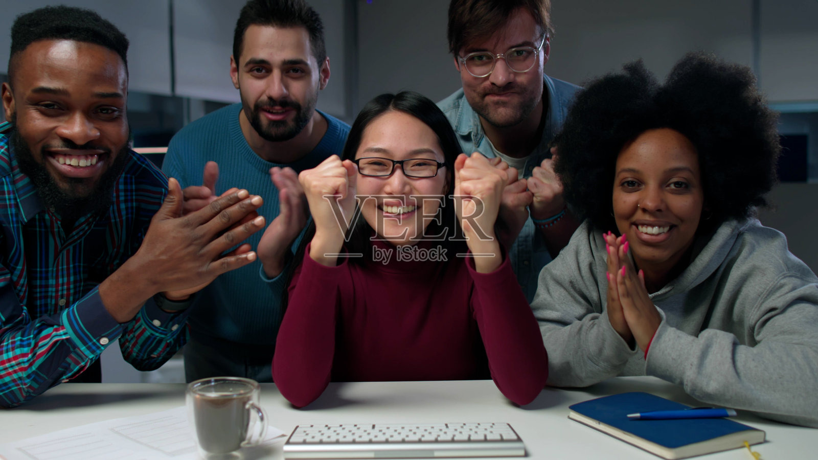 兴奋的多民族团队看着电脑屏幕，为庆祝成功而鼓掌照片摄影图片
