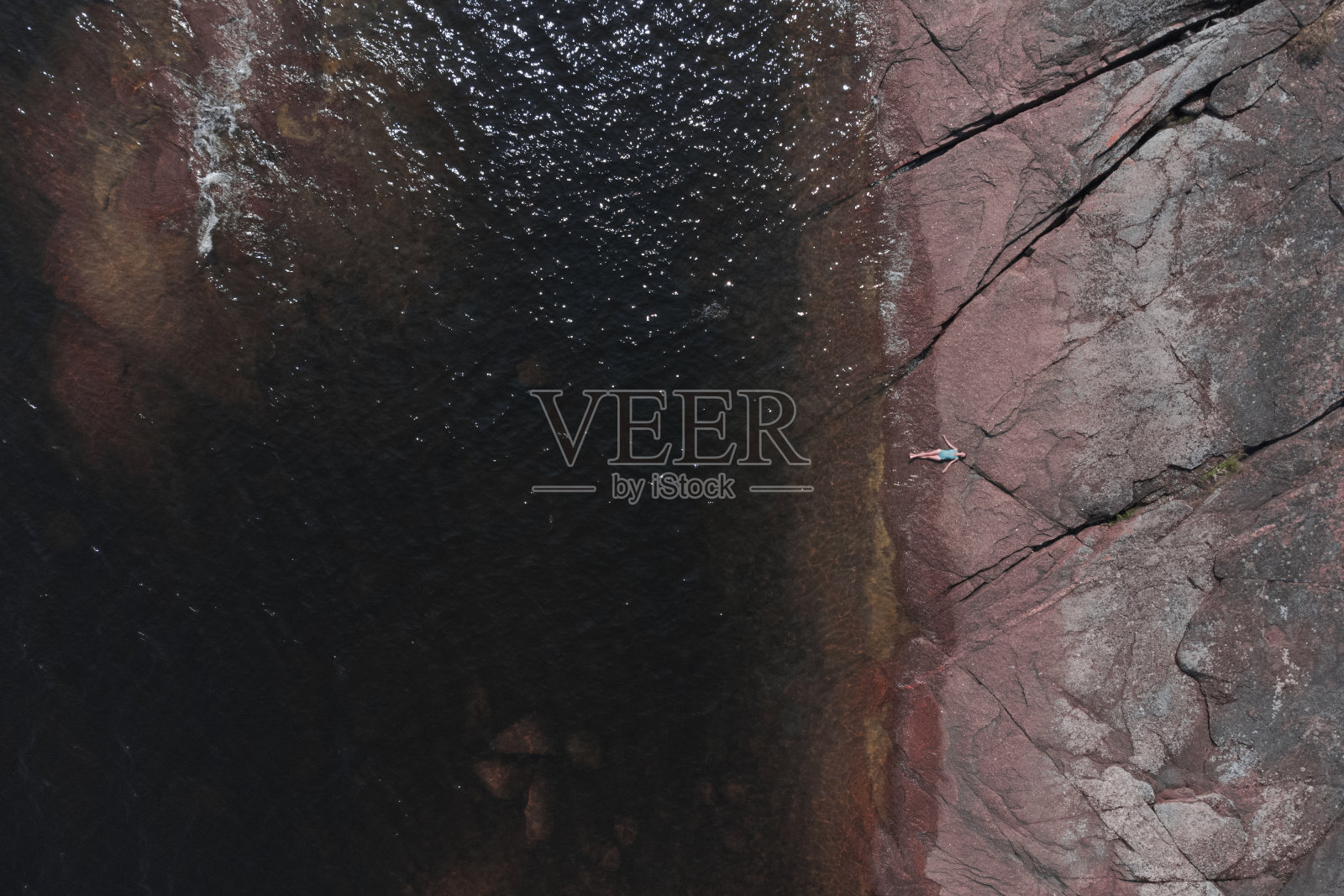 女人躺在花岗岩的海岸上照片摄影图片