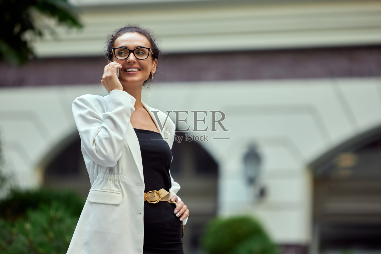 开朗，微笑，自信的商务女性走在办公室外面，讲着手机照片摄影图片
