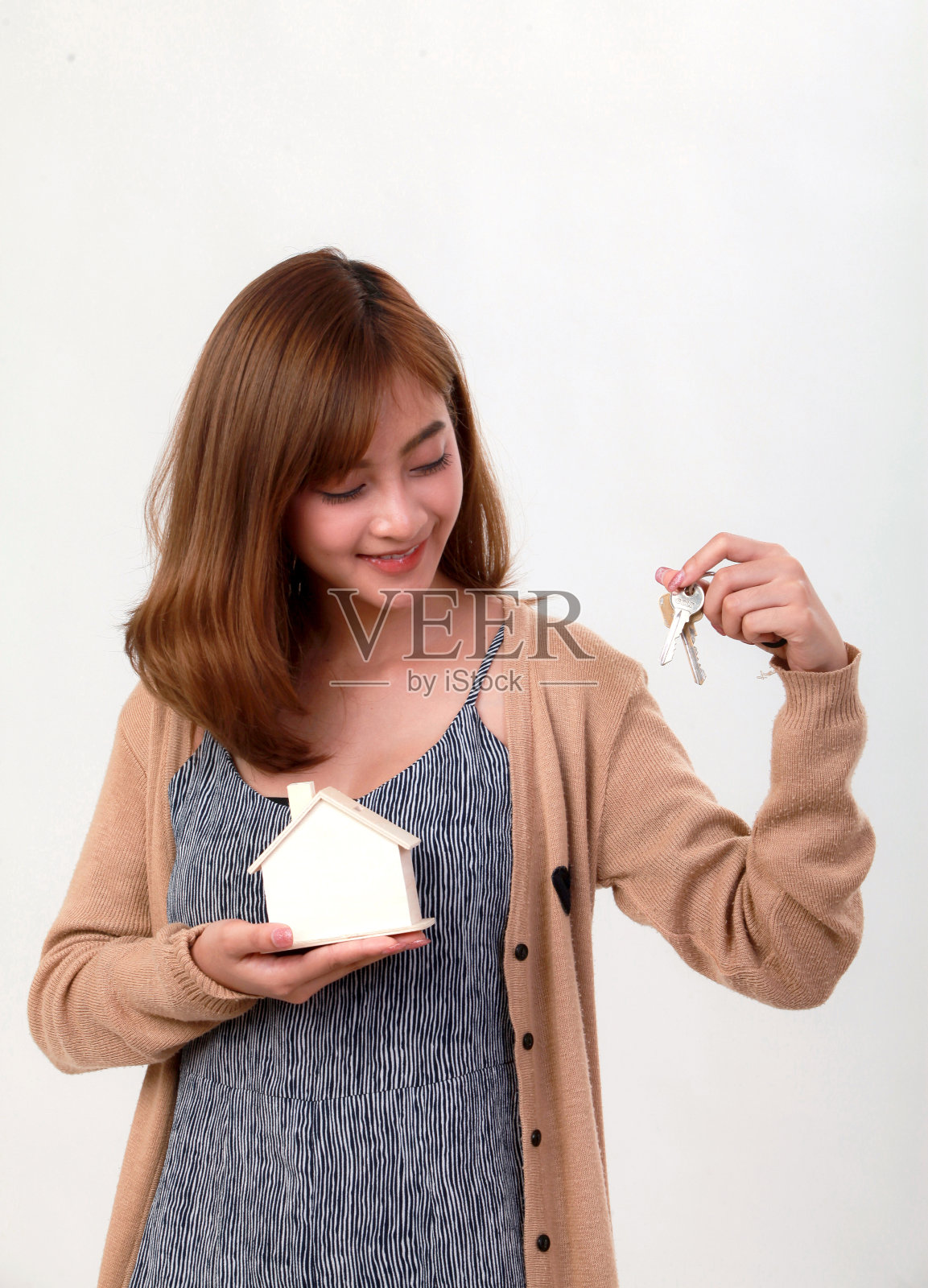 穿着休闲服的亚洲妇女手持白色背景的房屋模型照片摄影图片