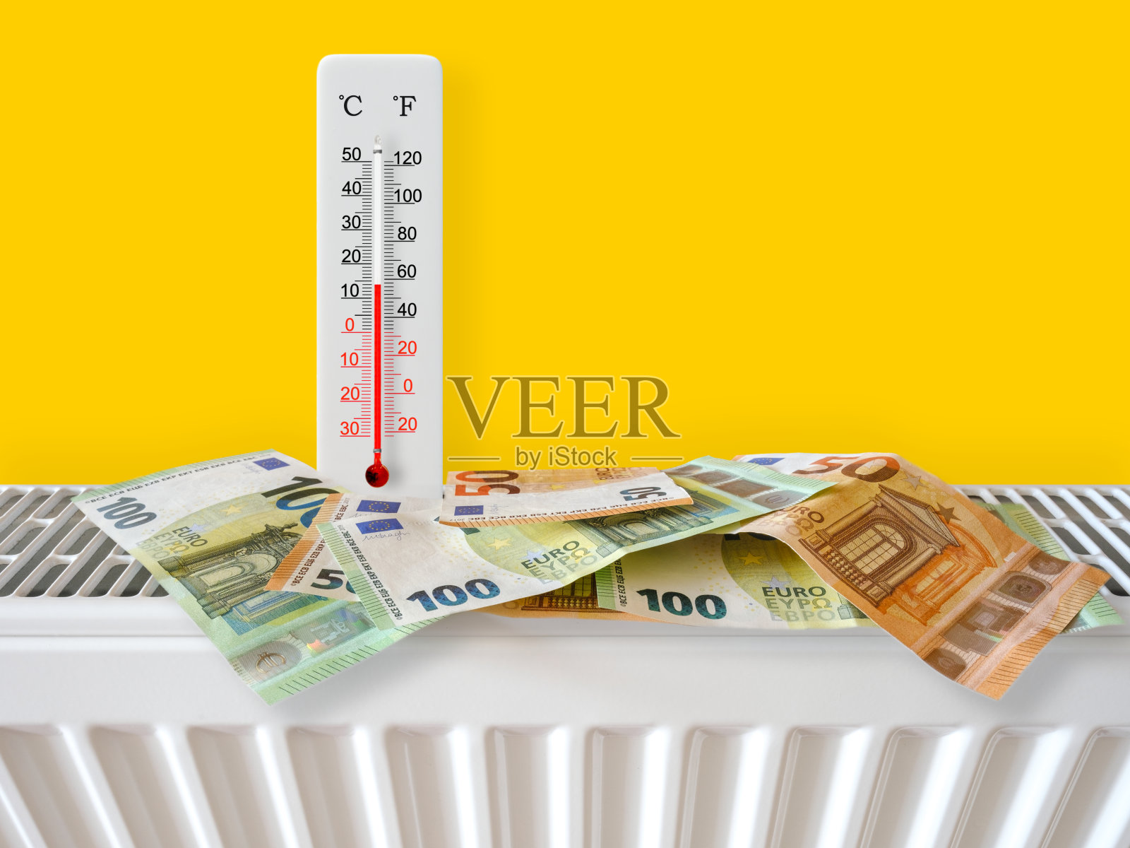 带有温度计的家用暖气散热器上印有欧元钞票。能源危机和昂贵的冬季取暖费用。高额的暖气和煤气账单。温度计显示气温为摄氏14度照片摄影图片