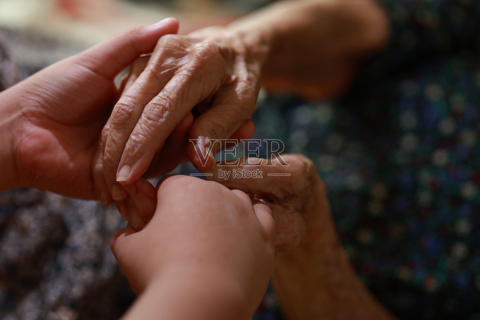 在一个特写镜头中，一个年轻人正牵着躺在床上的老年病人的手。照片摄影图片