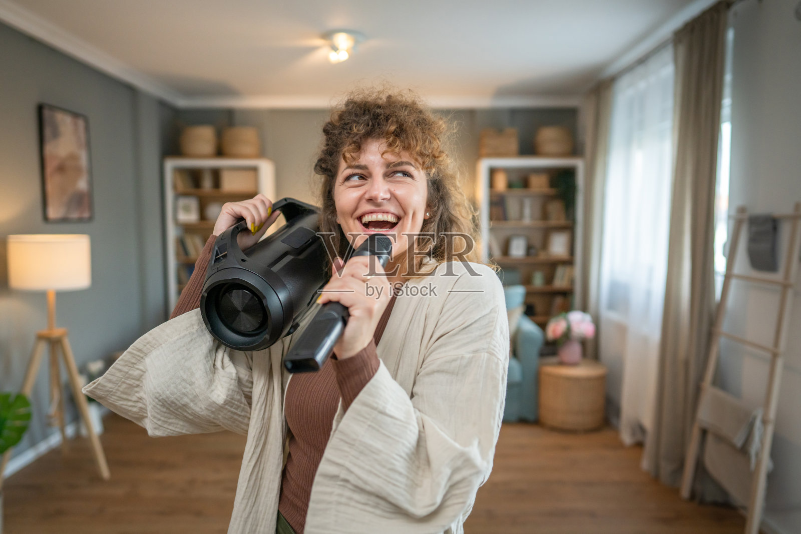 一名女子青年在家里拿着麦克风开心地笑着唱歌跳舞照片摄影图片