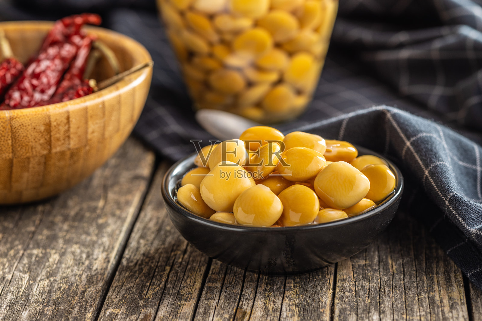 卤豆。木桌上碗里的腌菜。照片摄影图片