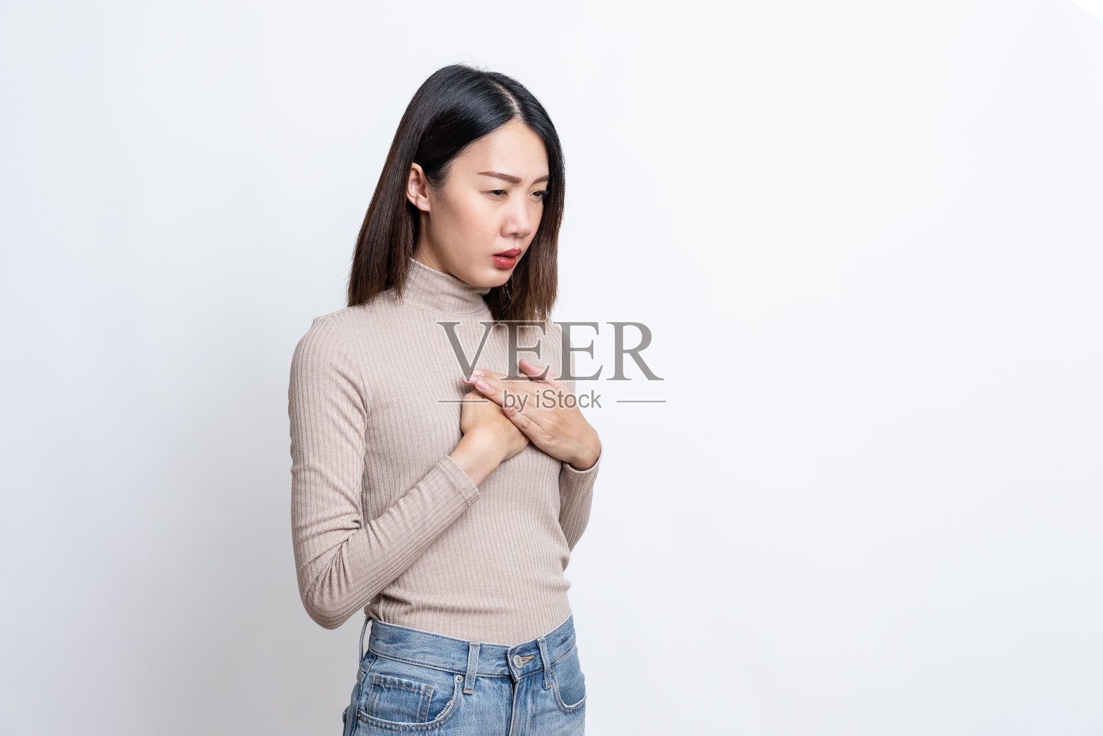 患病、压力大、忧心忡忡的亚洲女性的肖像，穿着格子衬衫，紧抓着胸口，承受着突如其来的剧痛，有心脏病发作和乳腺癌的风险。室内工作室拍摄孤立的白色背景。照片摄影图片