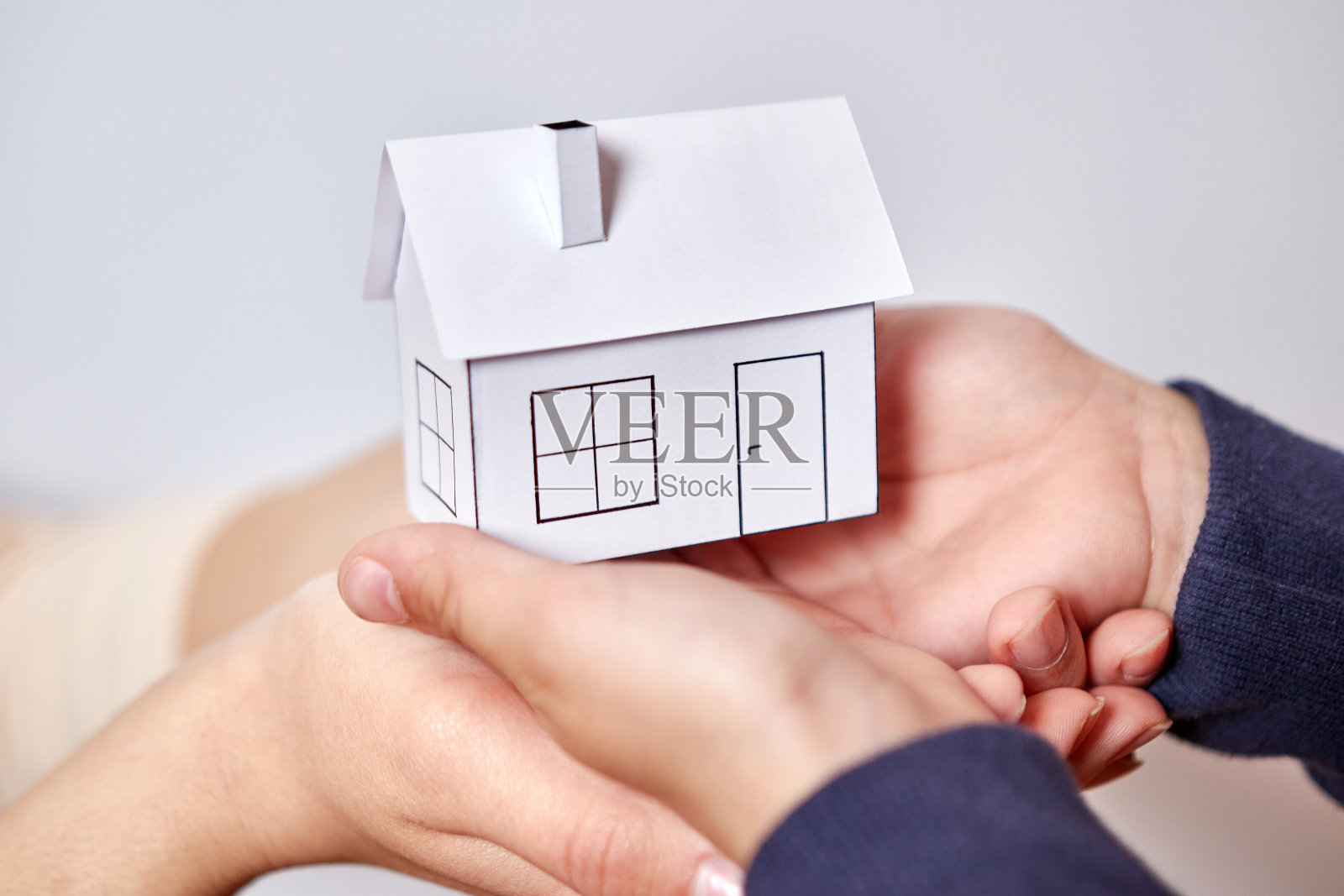 两双手手里拿着房子的模型。照片摄影图片