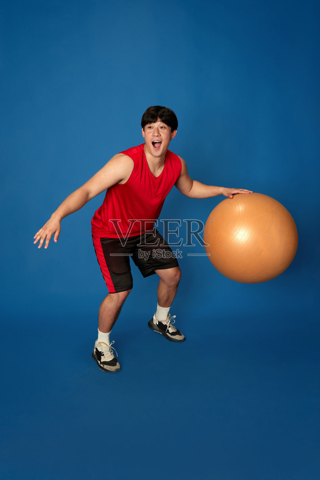 穿着运动服训练的年轻马的全身画像，在蓝色的工作室背景下玩健身球照片摄影图片