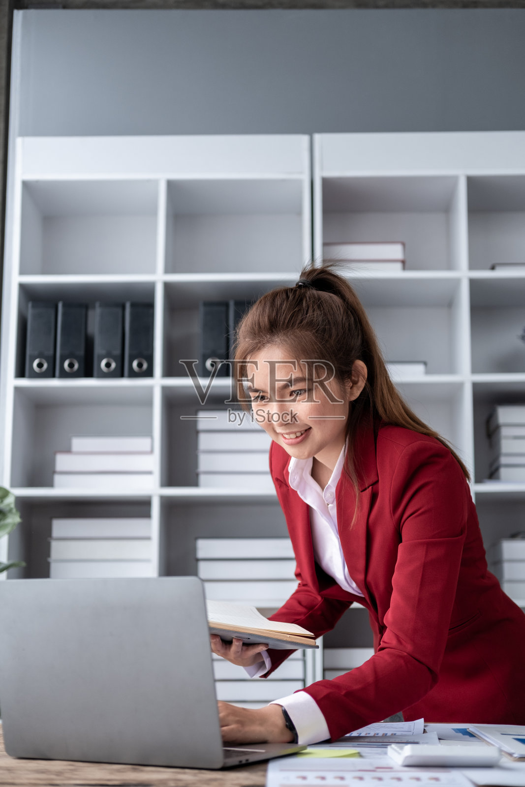年轻的亚洲快乐的职业商务女职员坐在办公桌旁，在电脑和计算器前工作，会计师在电脑上计算税率律所账户照片摄影图片
