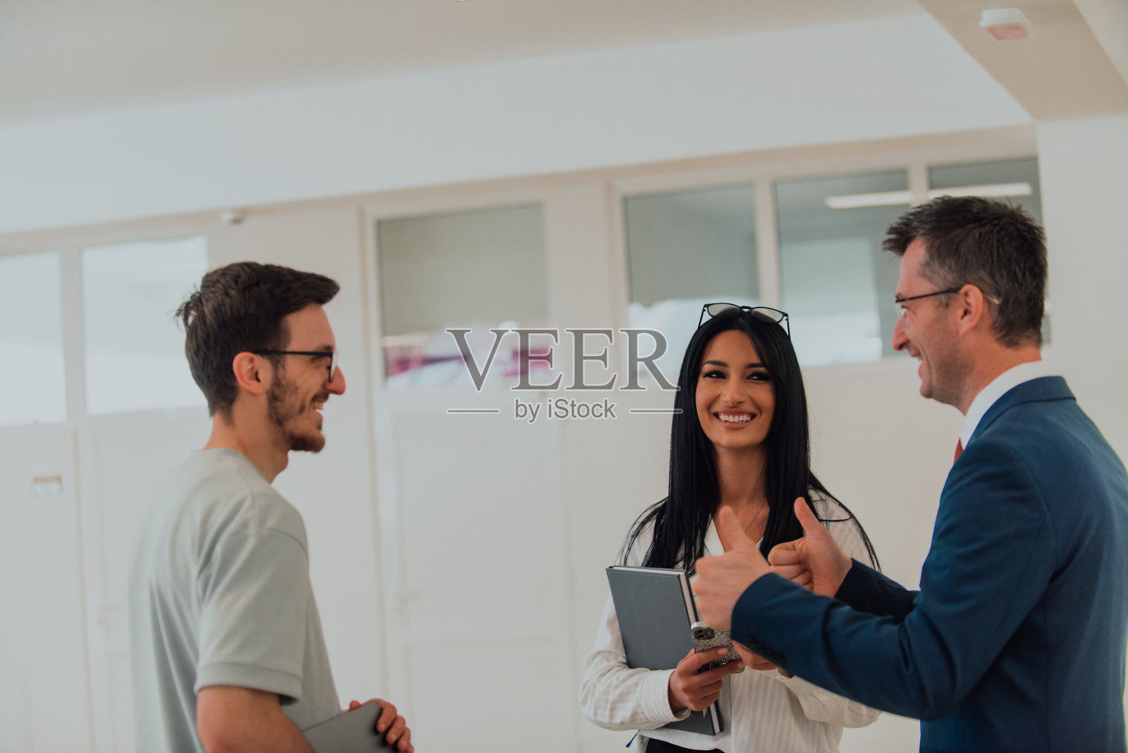 在一家大公司现代化宽敞的走廊里，导演与秘书和一名年轻的程序员交谈，讨论各种商业话题和项目。照片摄影图片