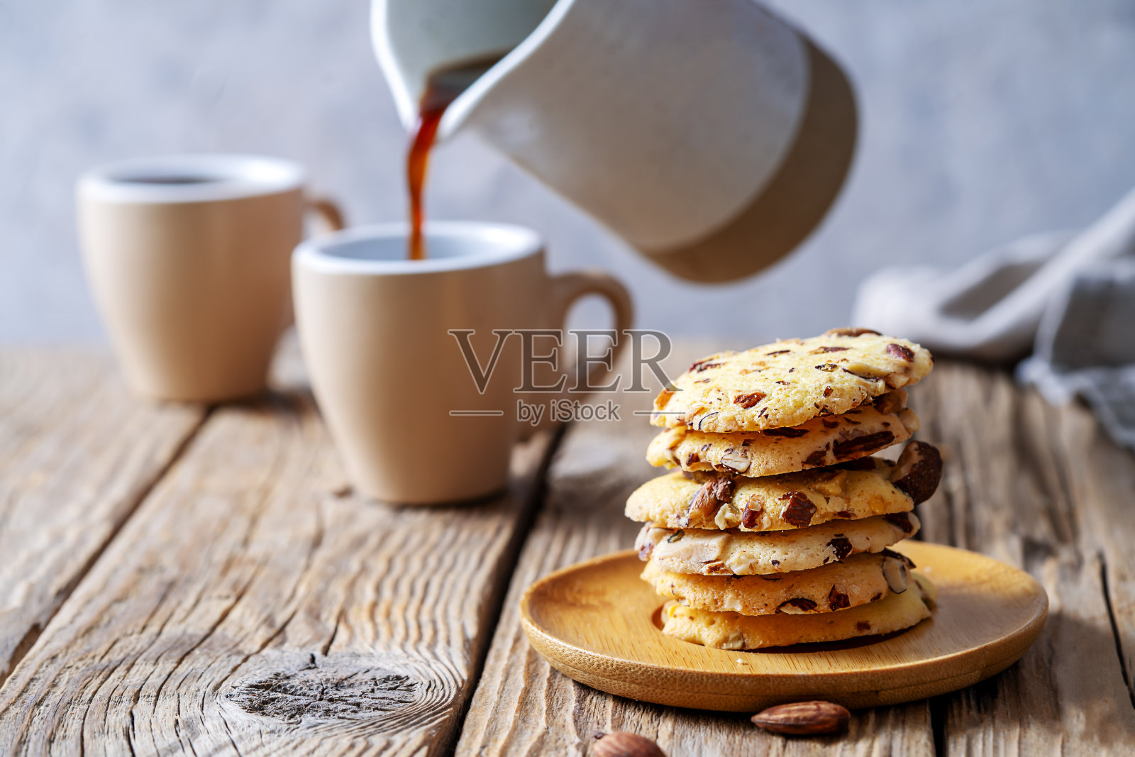 木制桌子上的佛罗伦萨饼干或佛罗伦萨杏仁饼干，配有咖啡杯和从马克杯倒咖啡的动作照片摄影图片
