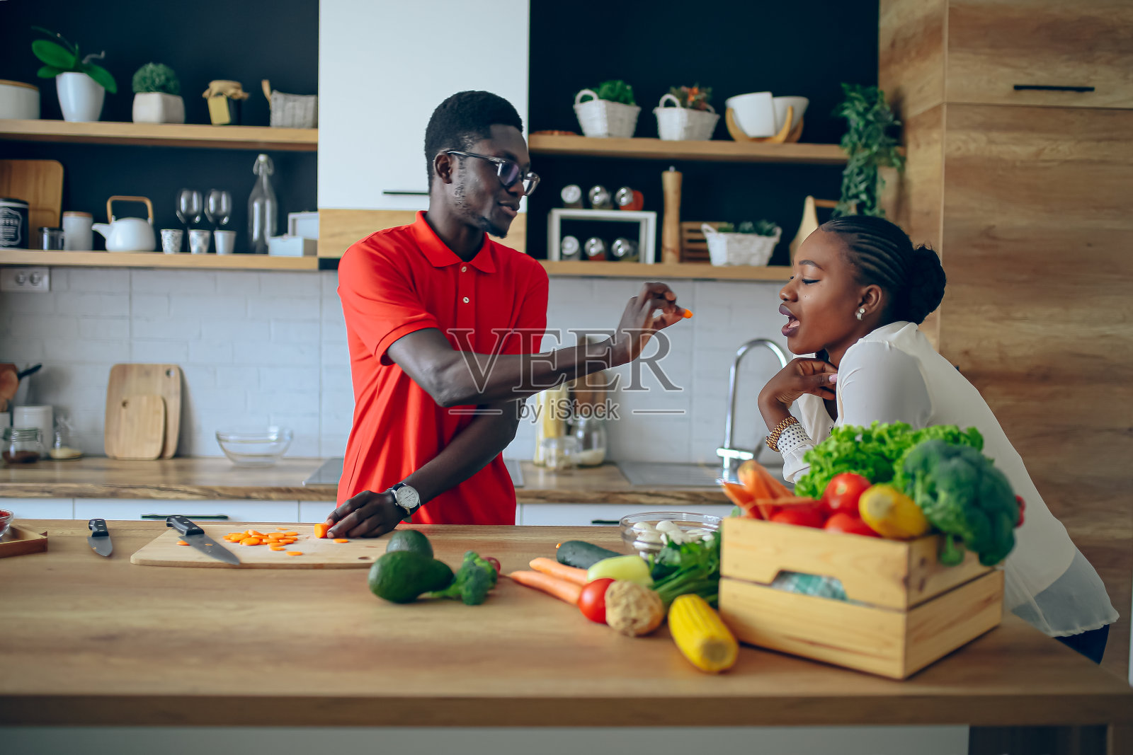 年轻的黑人厨师让他的女朋友品尝厨房里的食物照片摄影图片